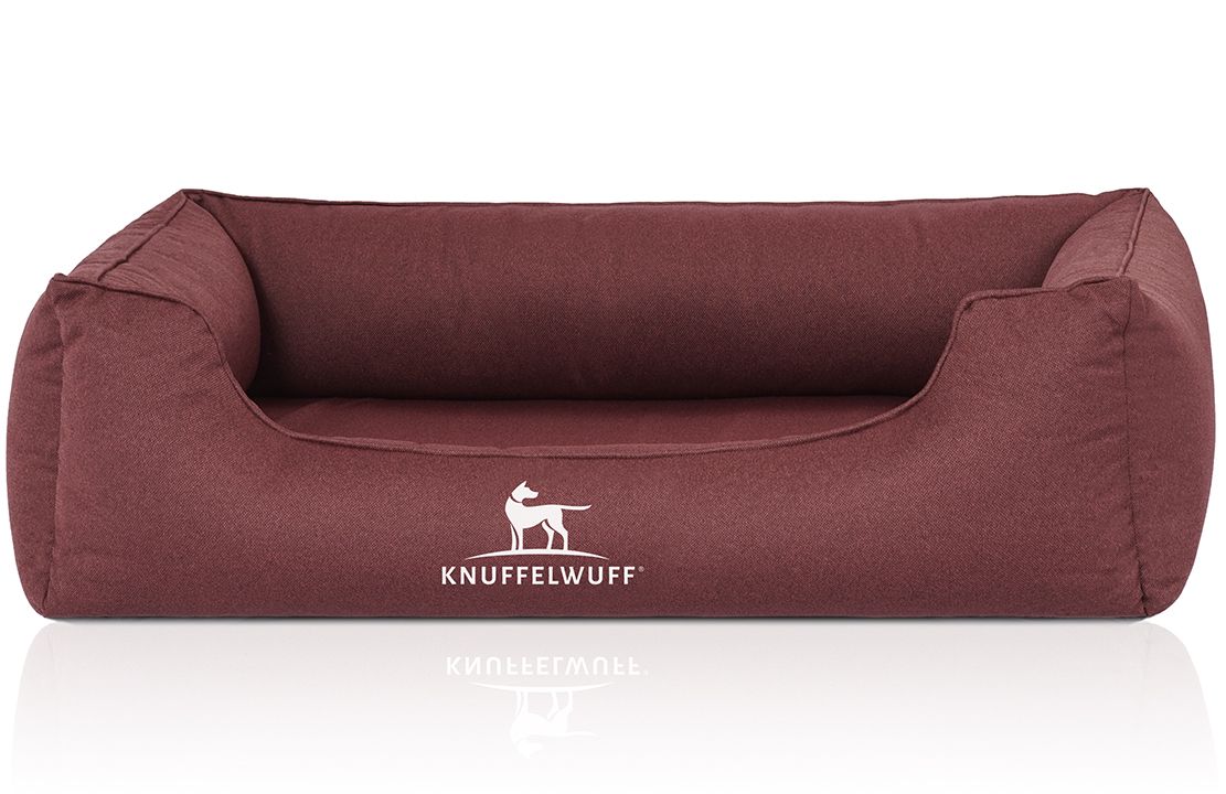 Burgunderfarbenes Hundebett mit erhöhtem Rand. Weißes Logo mit Hund und Schriftzug Knuffelwuff. Rechteckige Form.