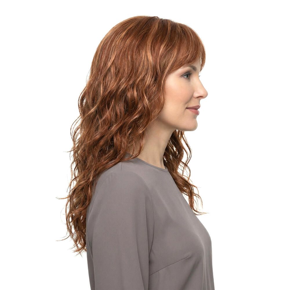 Perücke Kiky von trendhair. Rötlich-braune, gewellte Kunsthaarperücke mit Pony. Dreiviertelansicht einer Frau.