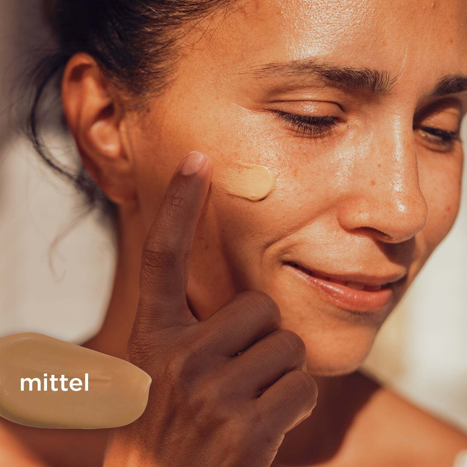 Frau trägt getöntes Serum auf ihr Gesicht auf. Daneben ein Klecks getöntes Serum mit der Aufschrift 'mittel'.