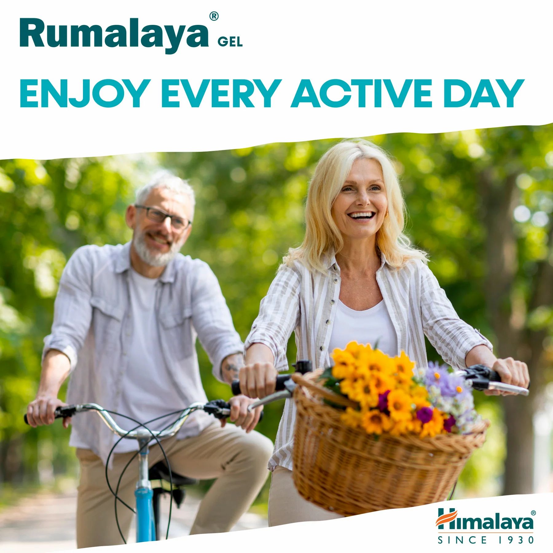 Älteres Paar fährt Fahrrad. Frau lächelt, Mann schaut. Korb mit Blumen. Hintergrund: Natur, Bäume.