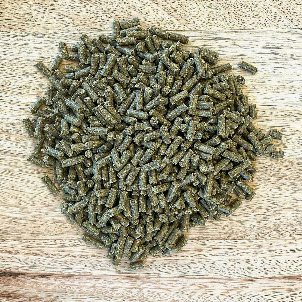 Haufen von grünlichen Pellets auf Holzuntergrund. Einzelne Pellets sind zylindrisch.