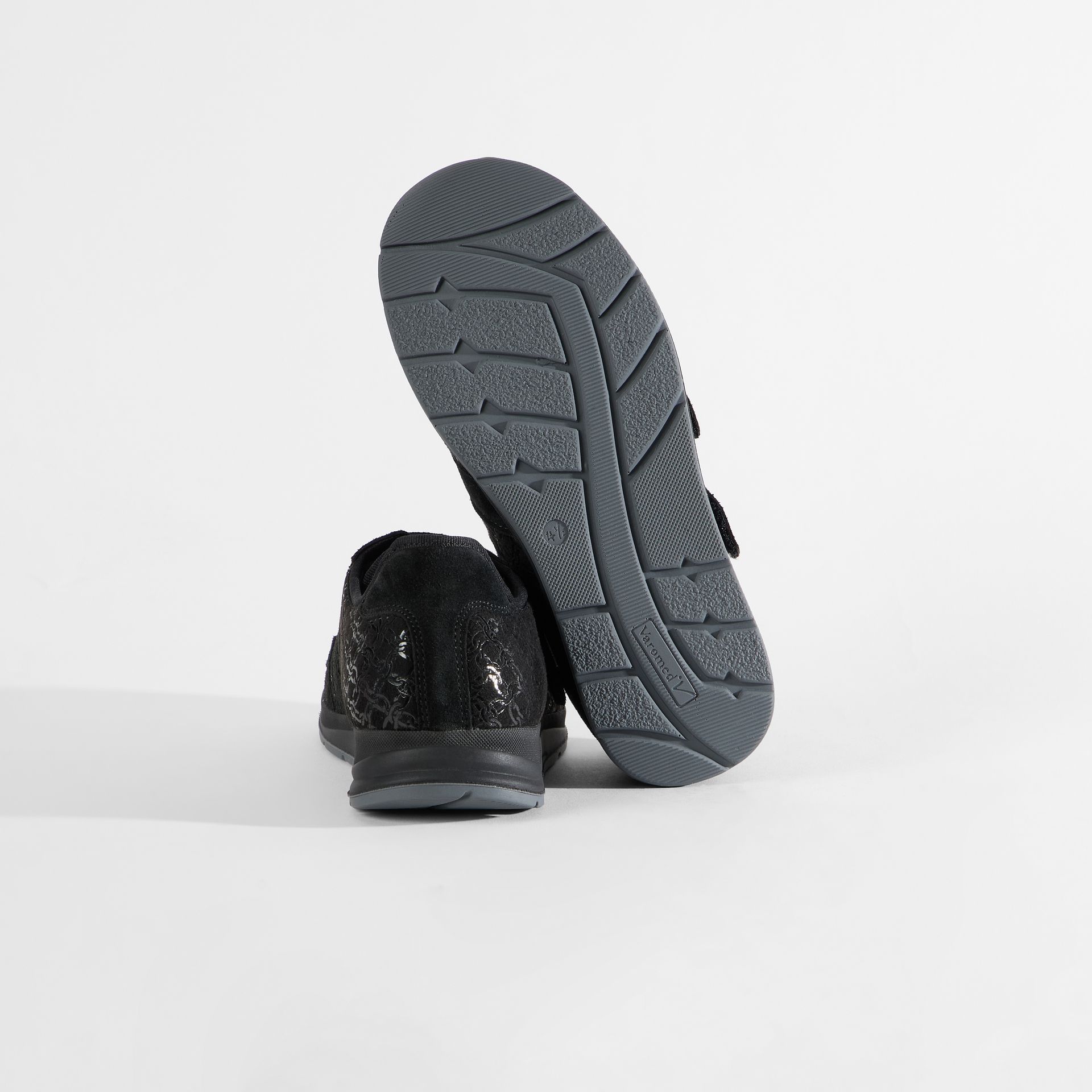 Schwarze Damenschuhe mit Klettverschluss und geprägtem Muster. Sohle von unten gezeigt.