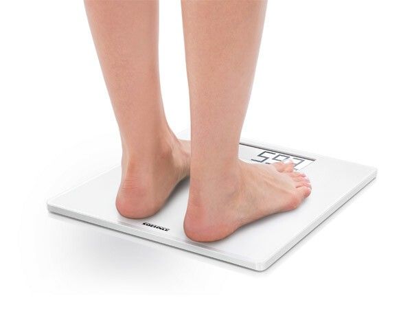 Weiße digitale Personenwaage. Füße stehen auf der Waage. Gewichtsanzeige.