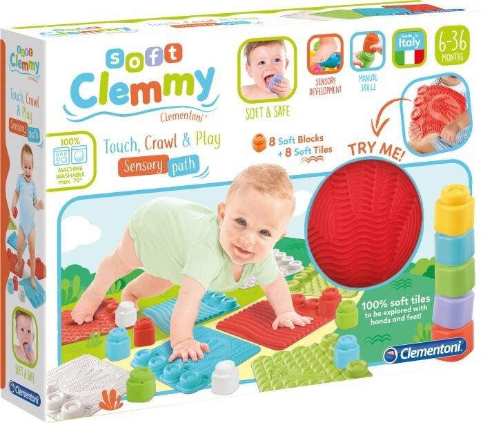Verpackung mit Clemmy-Spielmatte. Enthält weiche Blöcke, Fliesen und einen roten Ball. Baby krabbelt auf der Matte. Text: Soft Clemmy, 6-36 Monate.