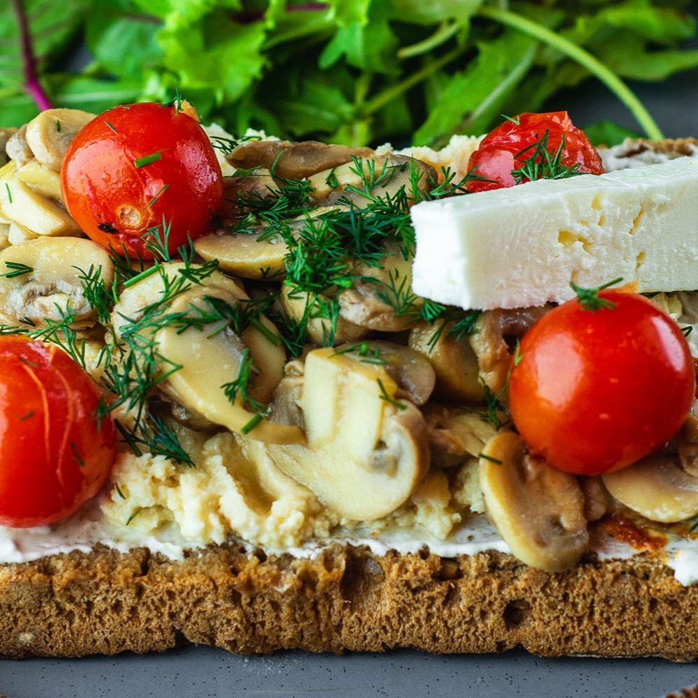Belegtes Brot mit Pilzen, Tomaten und Käse. Auf einem Teller. Dekoriert mit Dill.