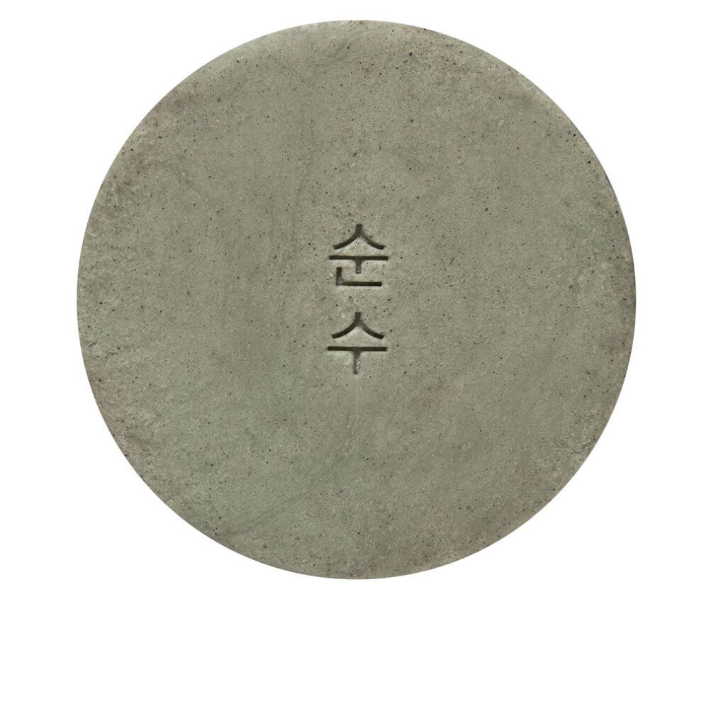 Runder, grauer Gegenstand mit eingeprägten Schriftzeichen. Oberfläche strukturiert. Auf weißem Hintergrund.