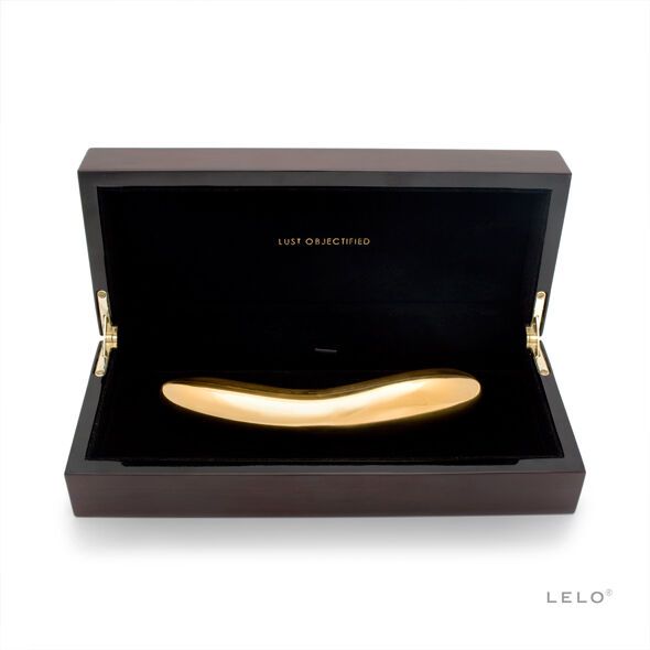 Goldfarbener Vibrator in einer Holzbox. Aufschrift 'LUST OBJECTIFIED'. LELO-Logo unten rechts.