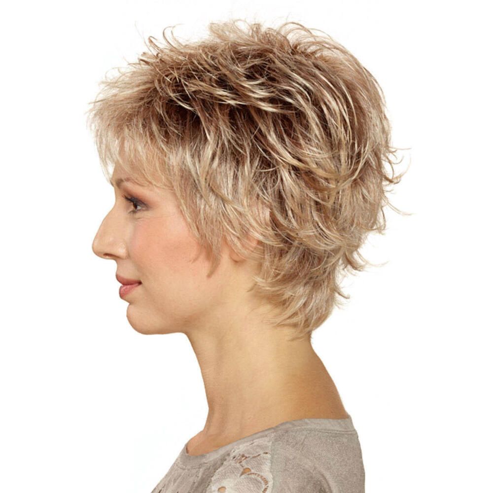 Kurzhaarperücke in Blondtönen. Seitenansicht. Die Frau trägt ein graues Oberteil.
