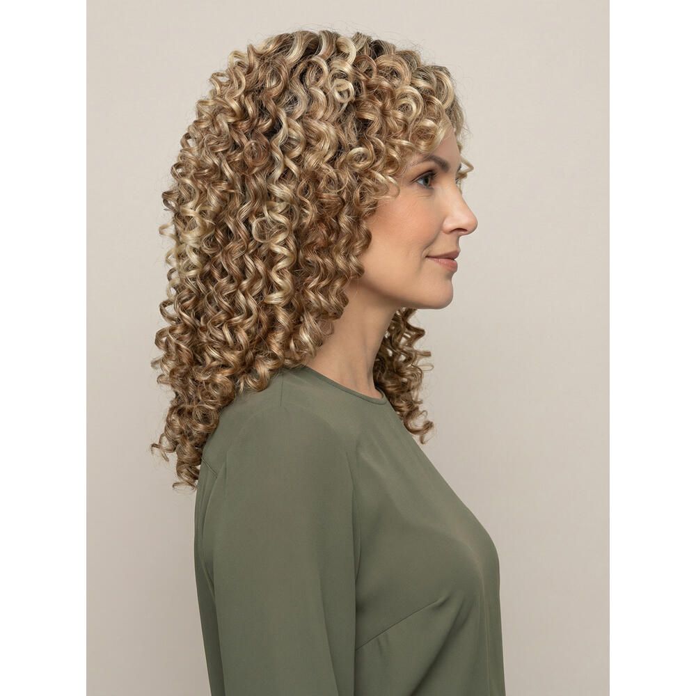 Frau mit lockiger Perücke. Seitenansicht. Blonde und braune Locken. Sie trägt ein grünes Oberteil.