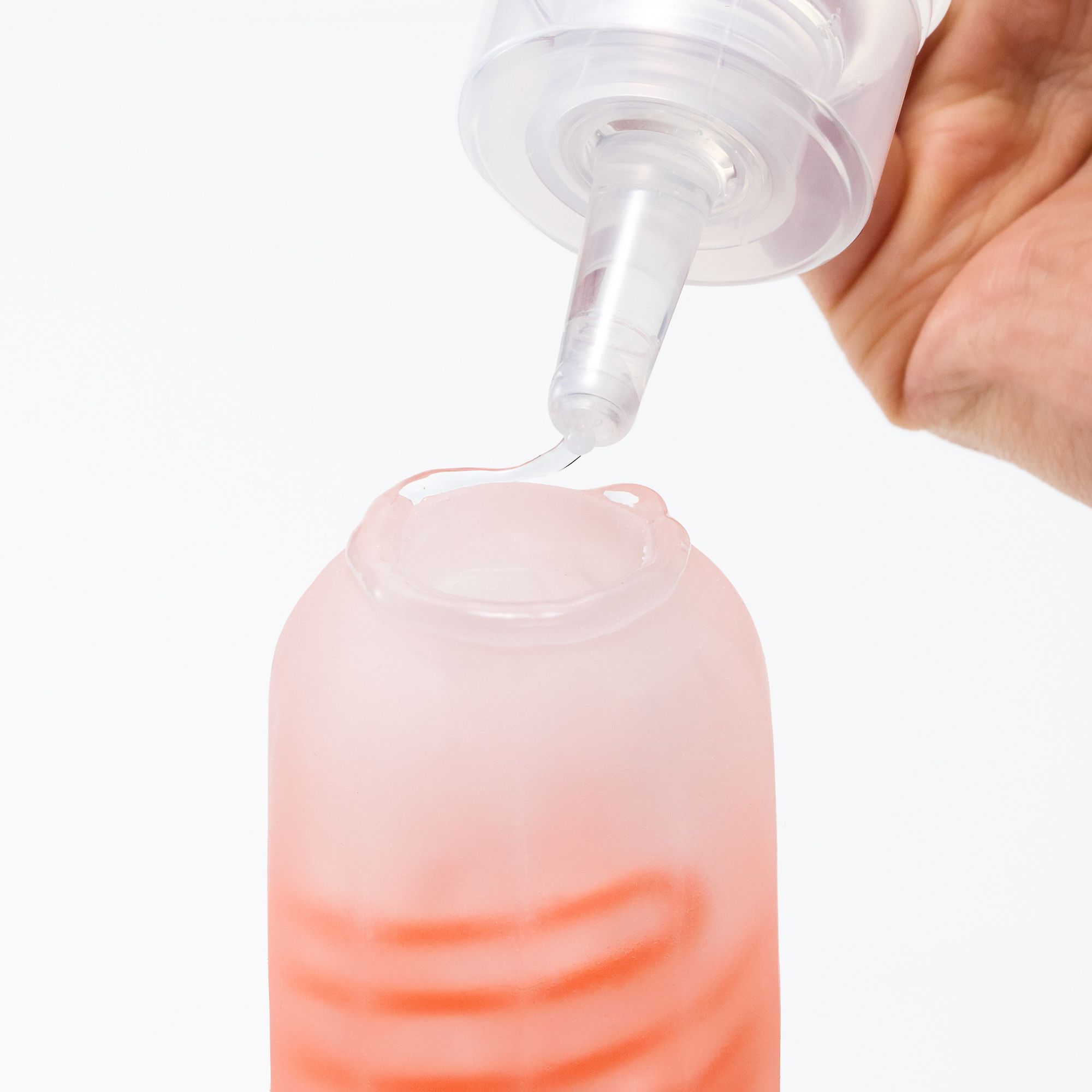Flüssigkeit tropft aus einer Spitze in einen Behälter mit roter Innenseite.
