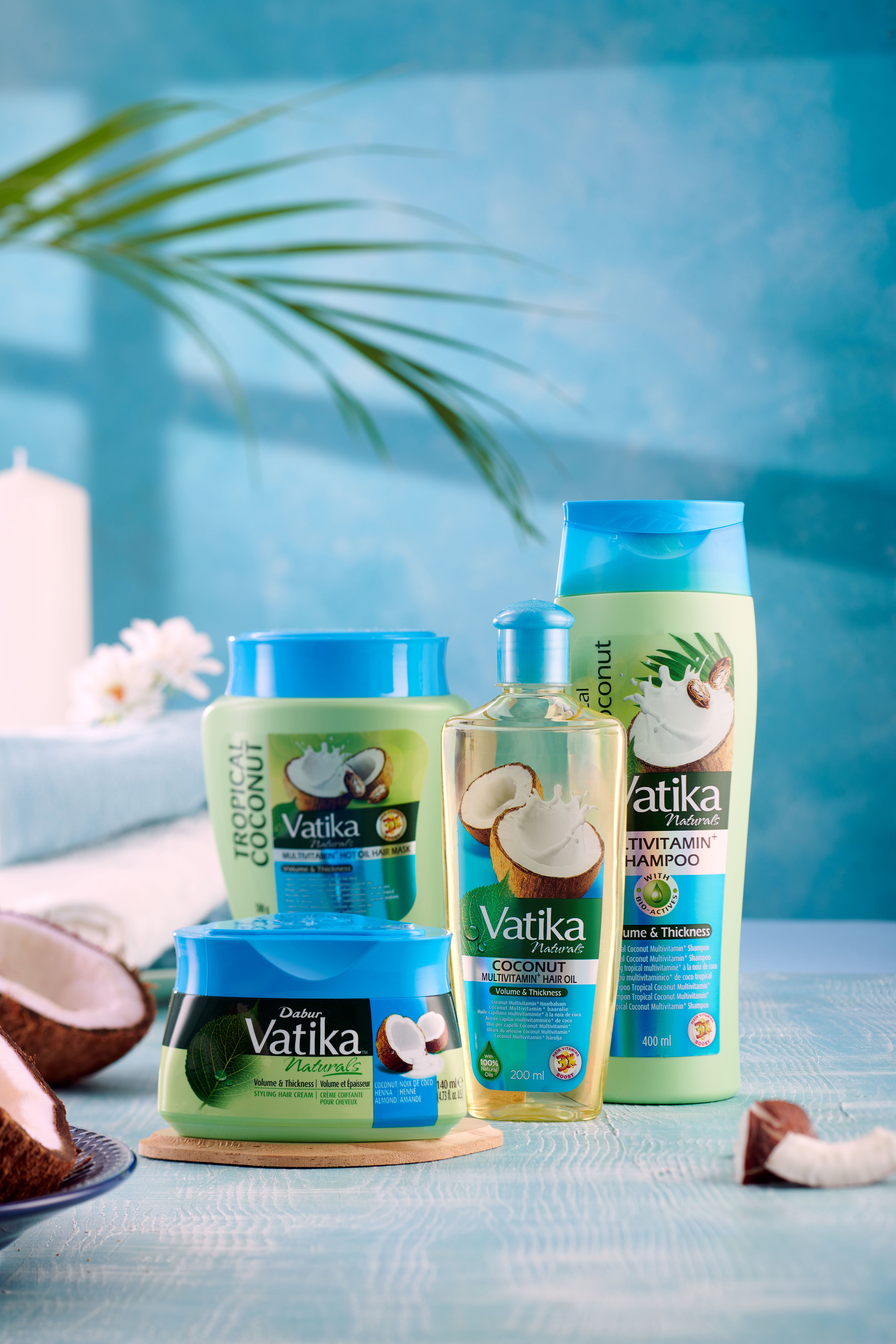 Produkt-Ensemble: Shampoo, Öl, Creme, Dose. Alle mit Vatika Naturals-Logo und Kokosnuss-Motiv. Auf blauem Hintergrund.