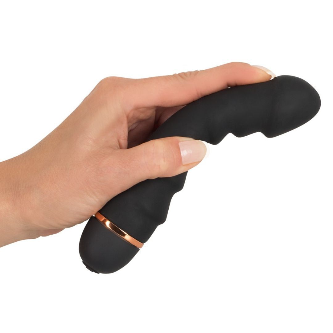 Schwarzer Vibrator in Hand gehalten. Geriffelte Oberfläche, kupferfarbener Ring.