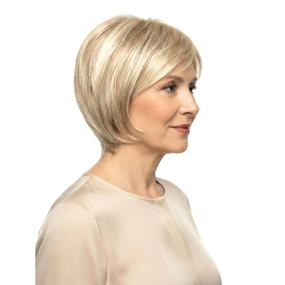 Blond gefärbte Perücke mit kurzem, gewelltem Haar. Seitenansicht einer Frau mit Perücke. Hellbeige Oberteil.