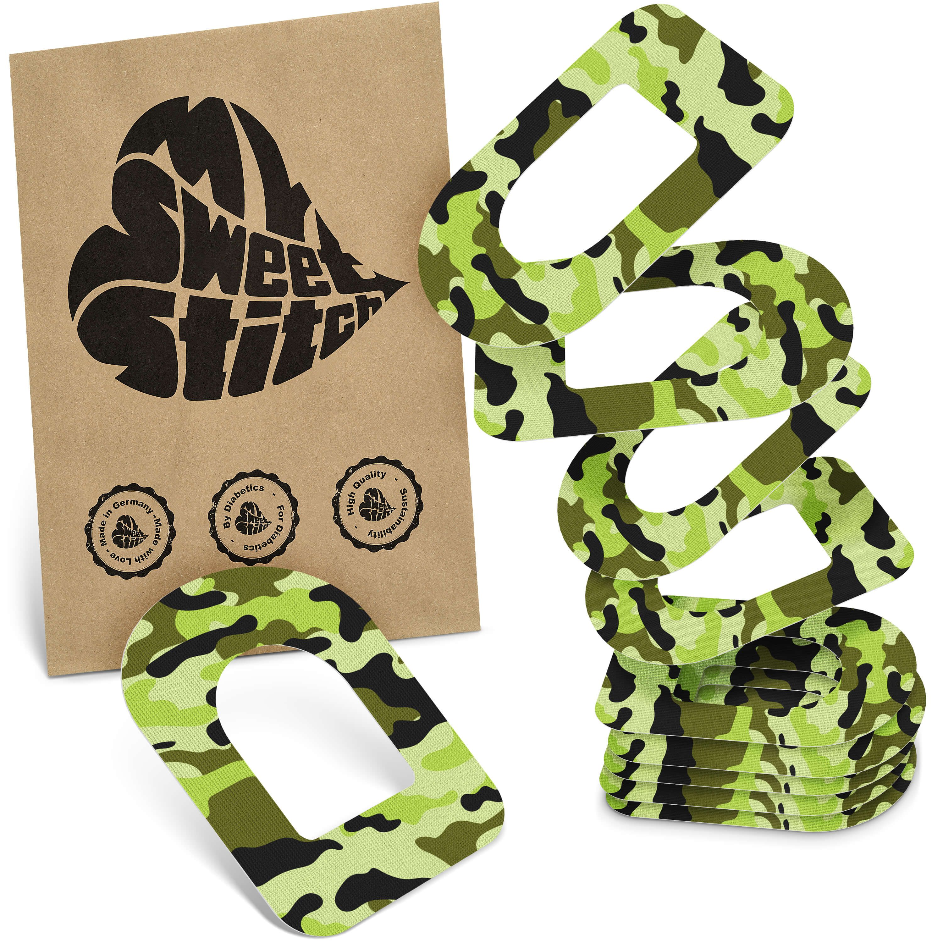 Ringpflaster mit Tarnmuster, neben brauner Verpackung mit Logo. Mehrere Pflaster gestapelt.