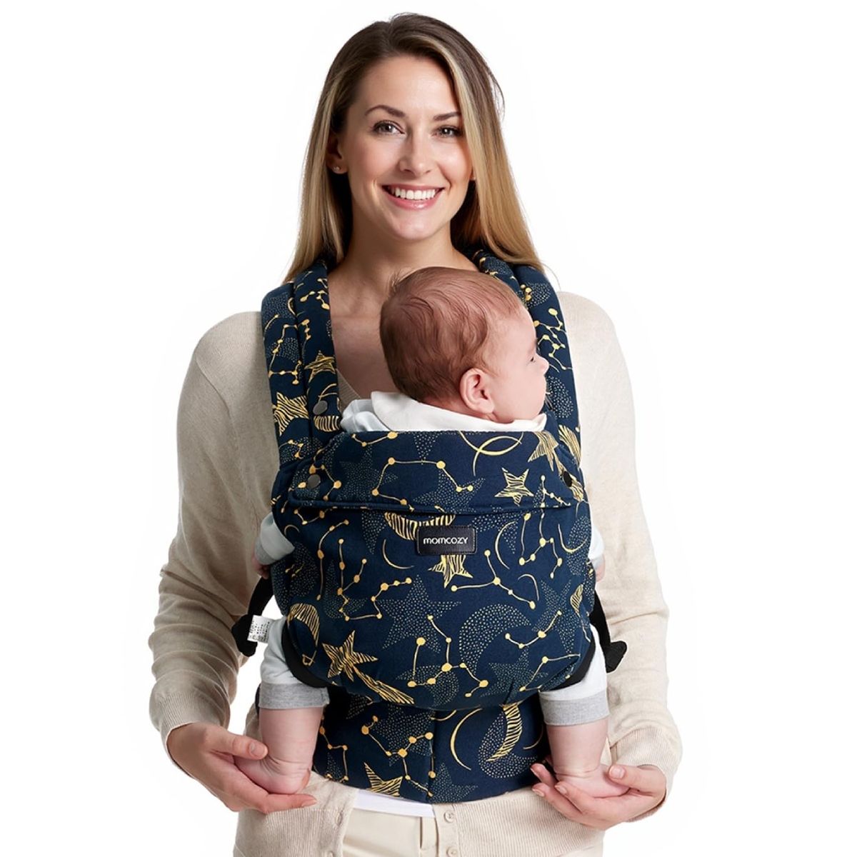 Frau hält Baby in einer Babytrage mit Sternenmuster. Baby blickt nach vorne. Momcozy-Logo sichtbar.