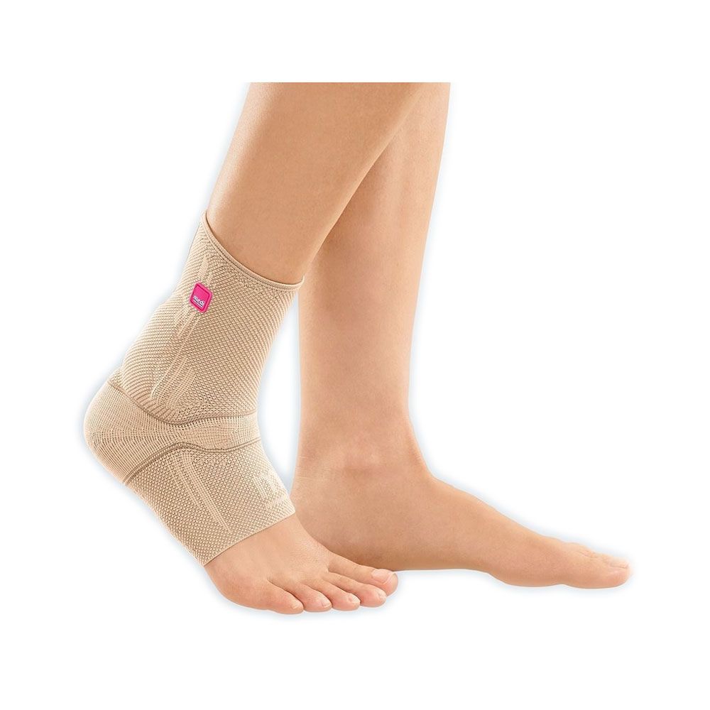 Beige Achillessehnenbandage am Fuß. Runder Logo-Aufnäher. Gehalten von einer Person.