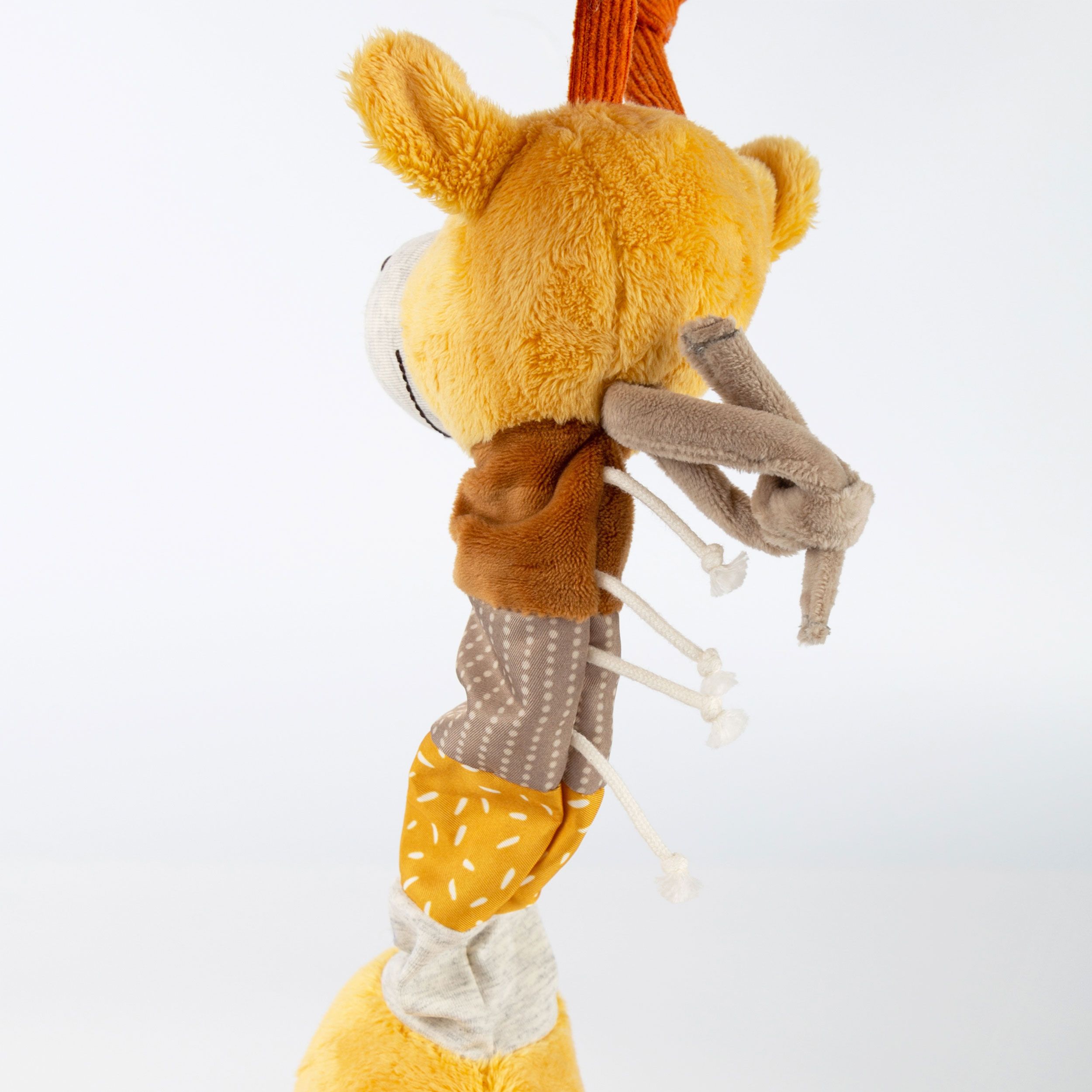 Nahaufnahme einer gelben Stoffgiraffe. Verschiedene Stoffe und Muster. Schnur zum Ziehen. Grauer Mund.