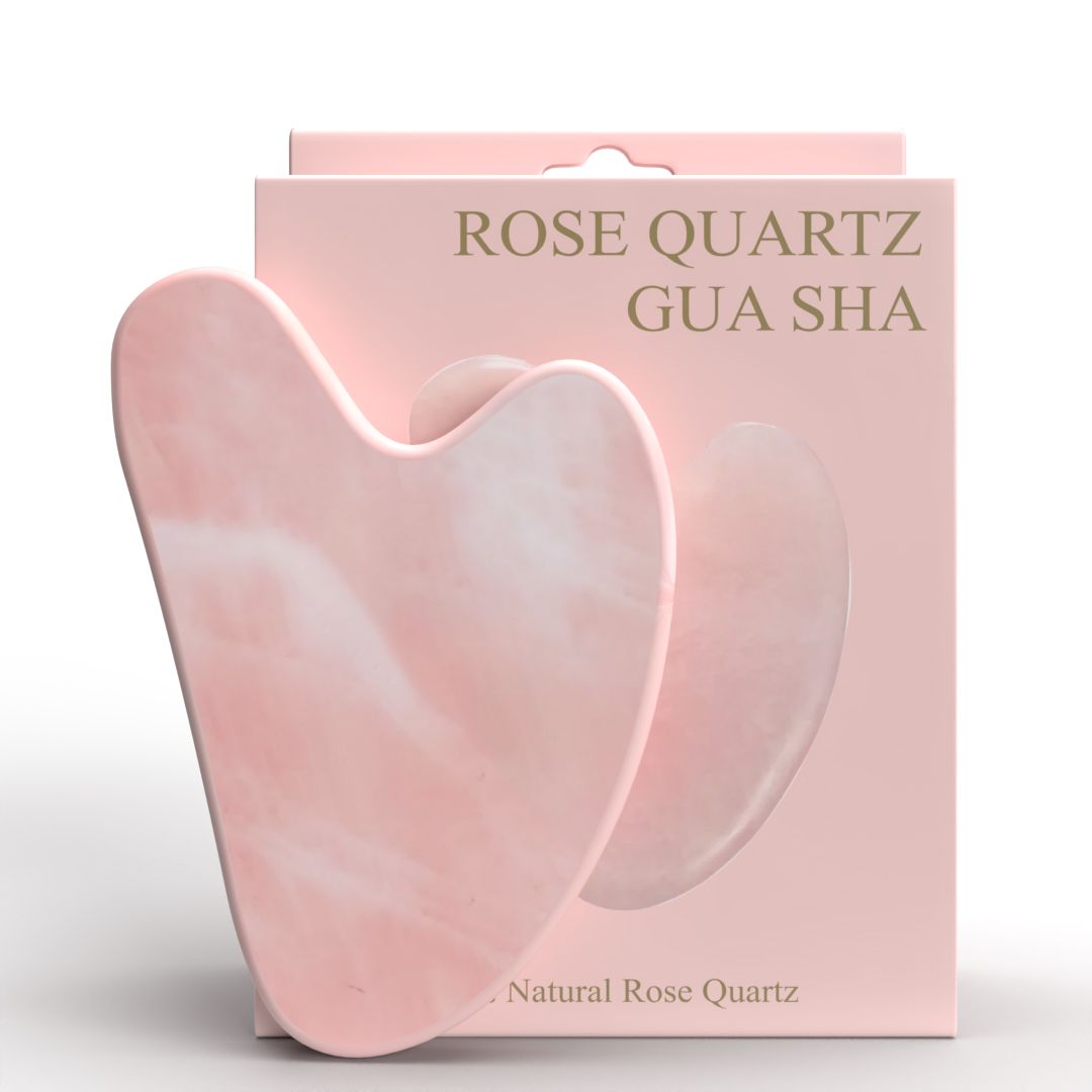 Rosenquarz Gua Sha. Herzförmig, rosa. Auf rosa Verpackung mit Aufschrift 'Rose Quartz Gua Sha'.