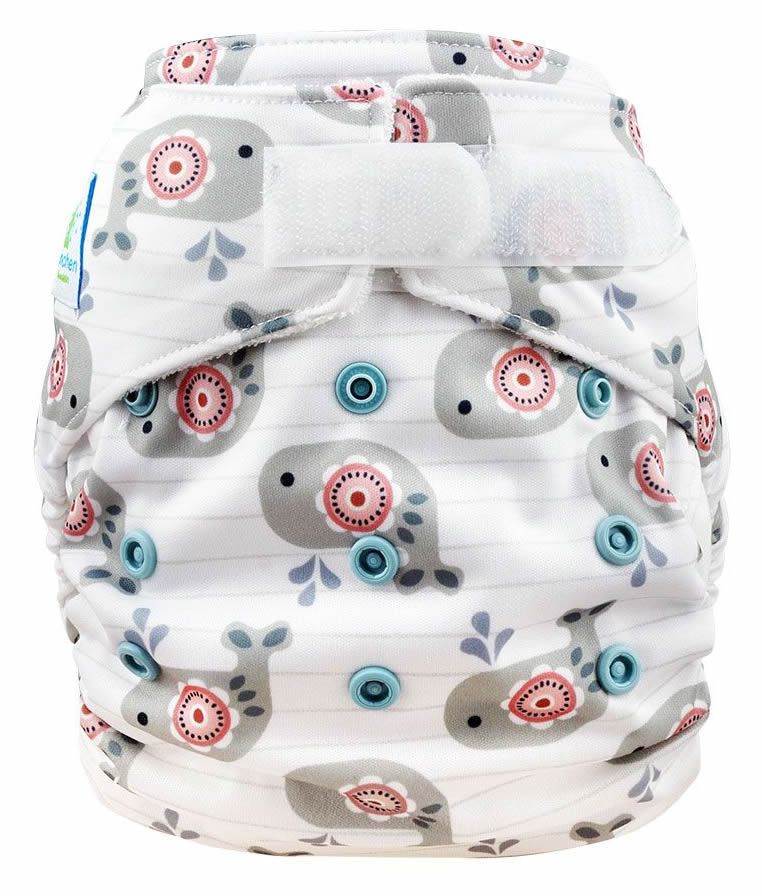 Weiße Stoffwindel mit Wal-Muster und Klettverschluss. Blaue Druckknöpfe und das Logo "Blümchen" sind sichtbar.