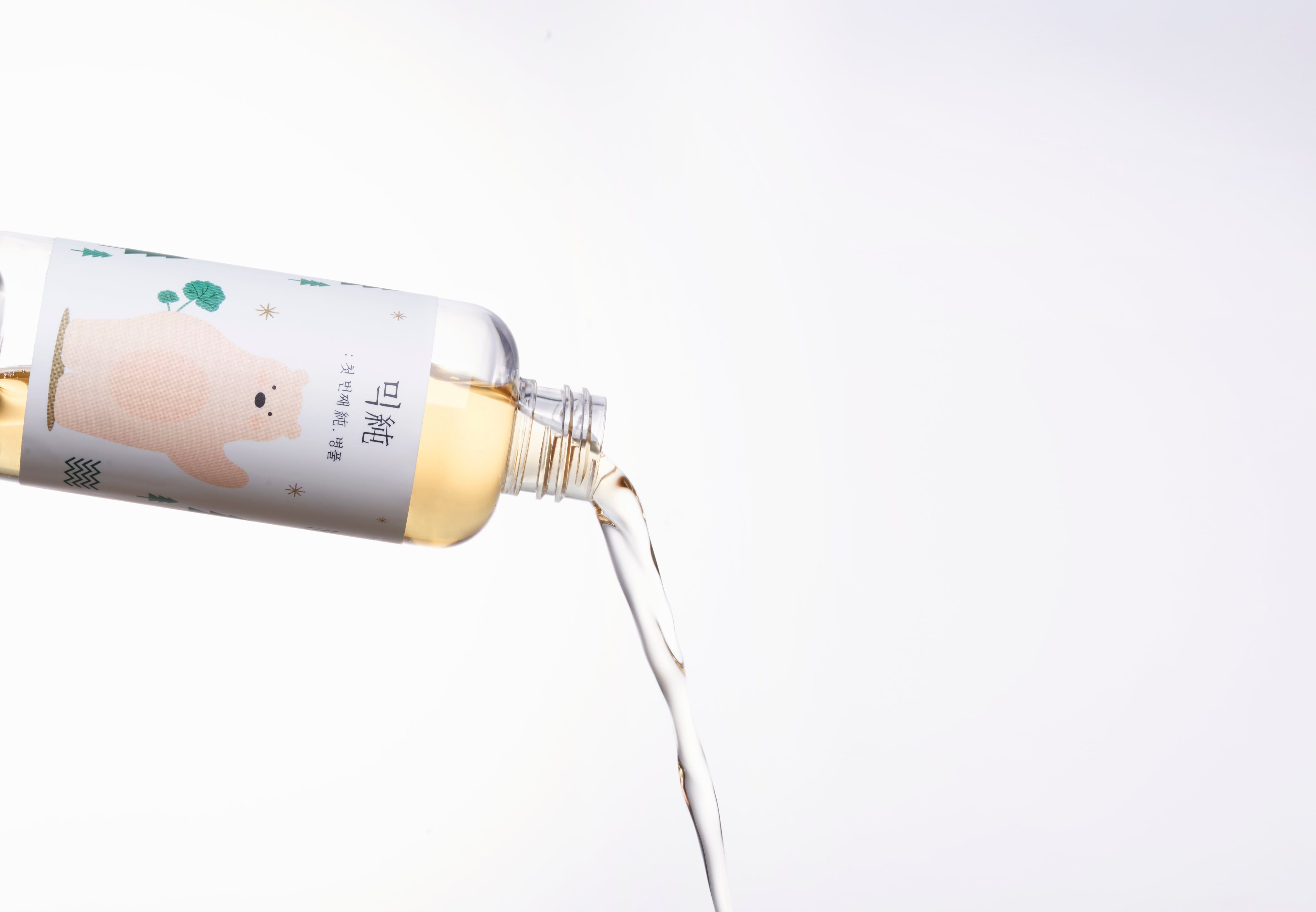 Flüssigkeit wird aus einer Flasche gegossen. Weißer Hintergrund.