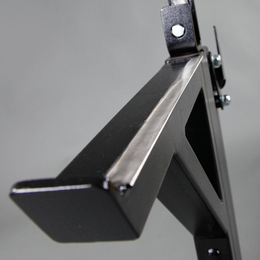 Nahaufnahme einer schwarzen Metallkonstruktion. Dreieckige Form mit einer rechteckigen Auflage. Grauer Hintergrund.