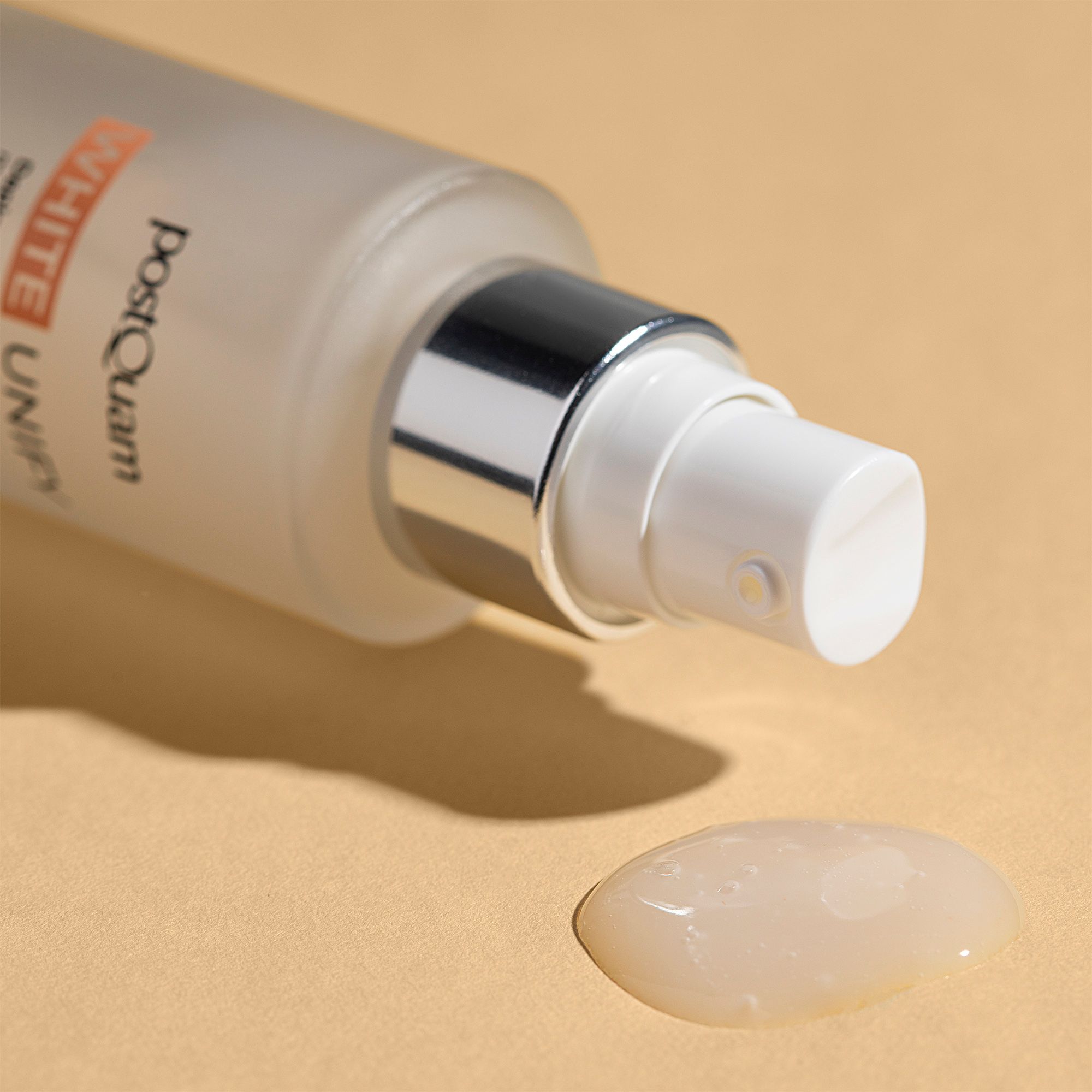 Serumflasche mit Sprühkopf und Serumtropfen. Aufschrift: PostQuam, White Unify. Serum ist farblos.