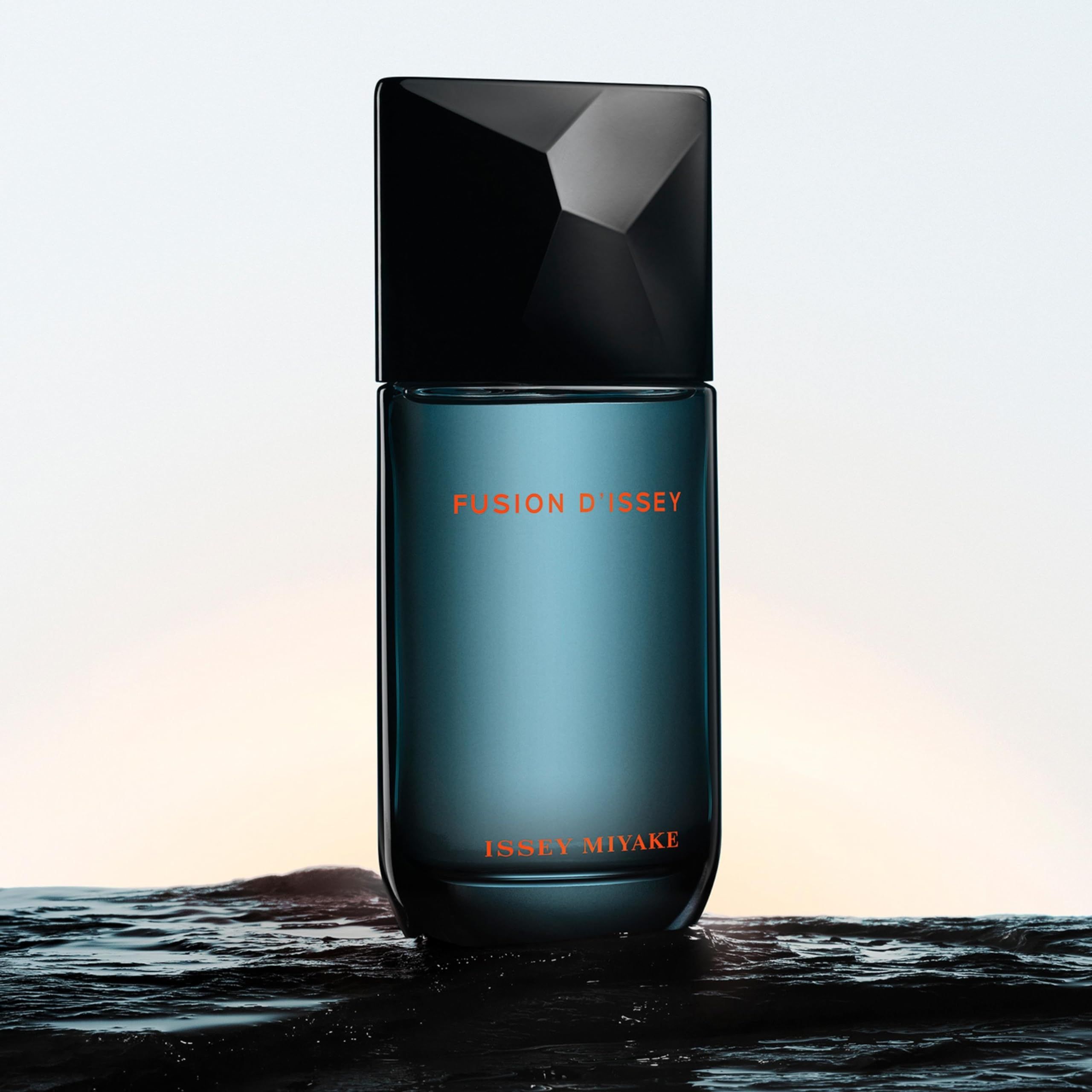 Issey Miyake Fusion d'Issey Eau de Toilette. Blauer Flakon mit schwarzem Deckel. Text: Fusion d'Issey, Issey Miyake. Hintergrund: Wasser.