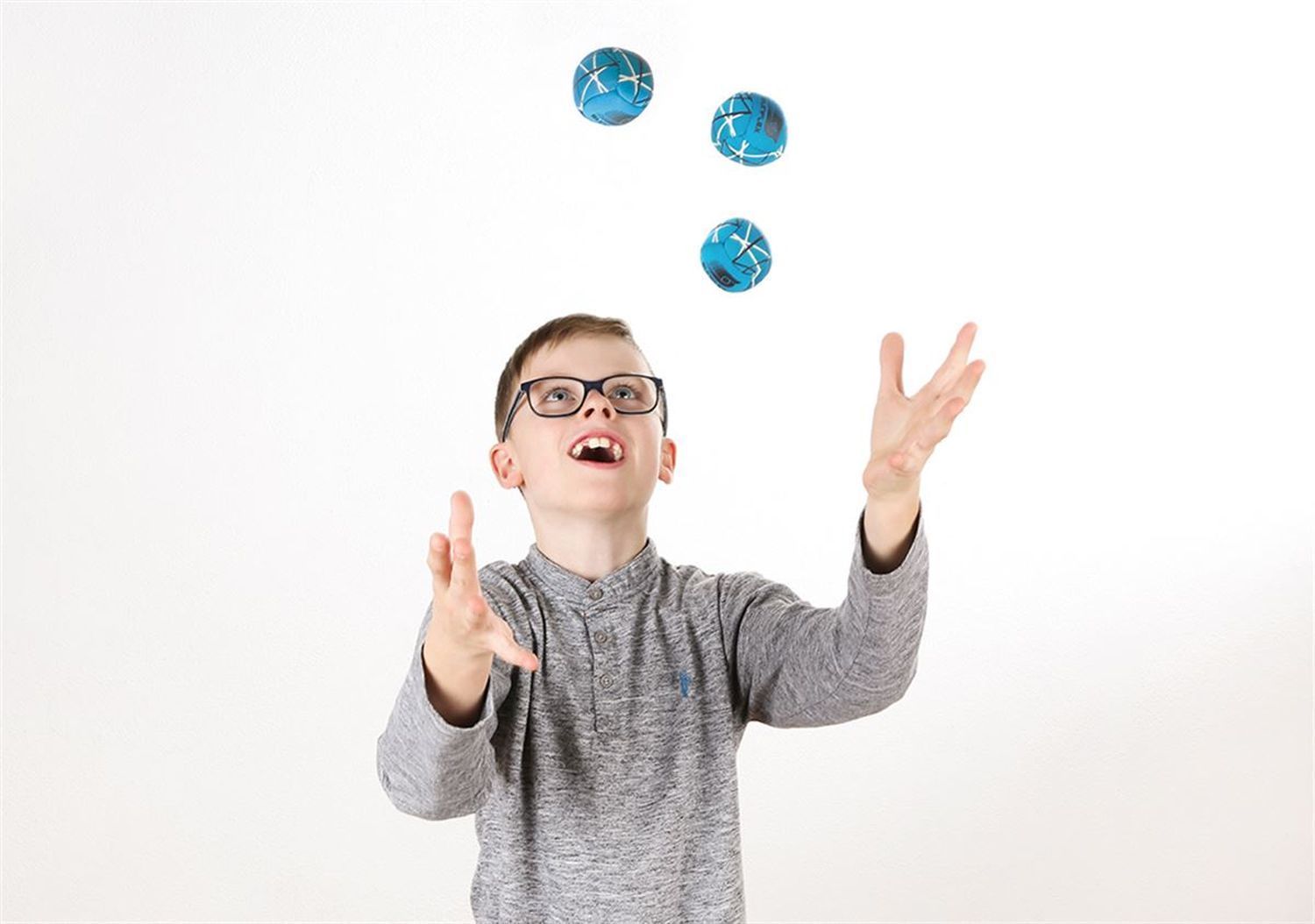 Ein Junge jongliert mit drei blauen Sunflex Funball Neoremi Circle. Der Hintergrund ist weiß.