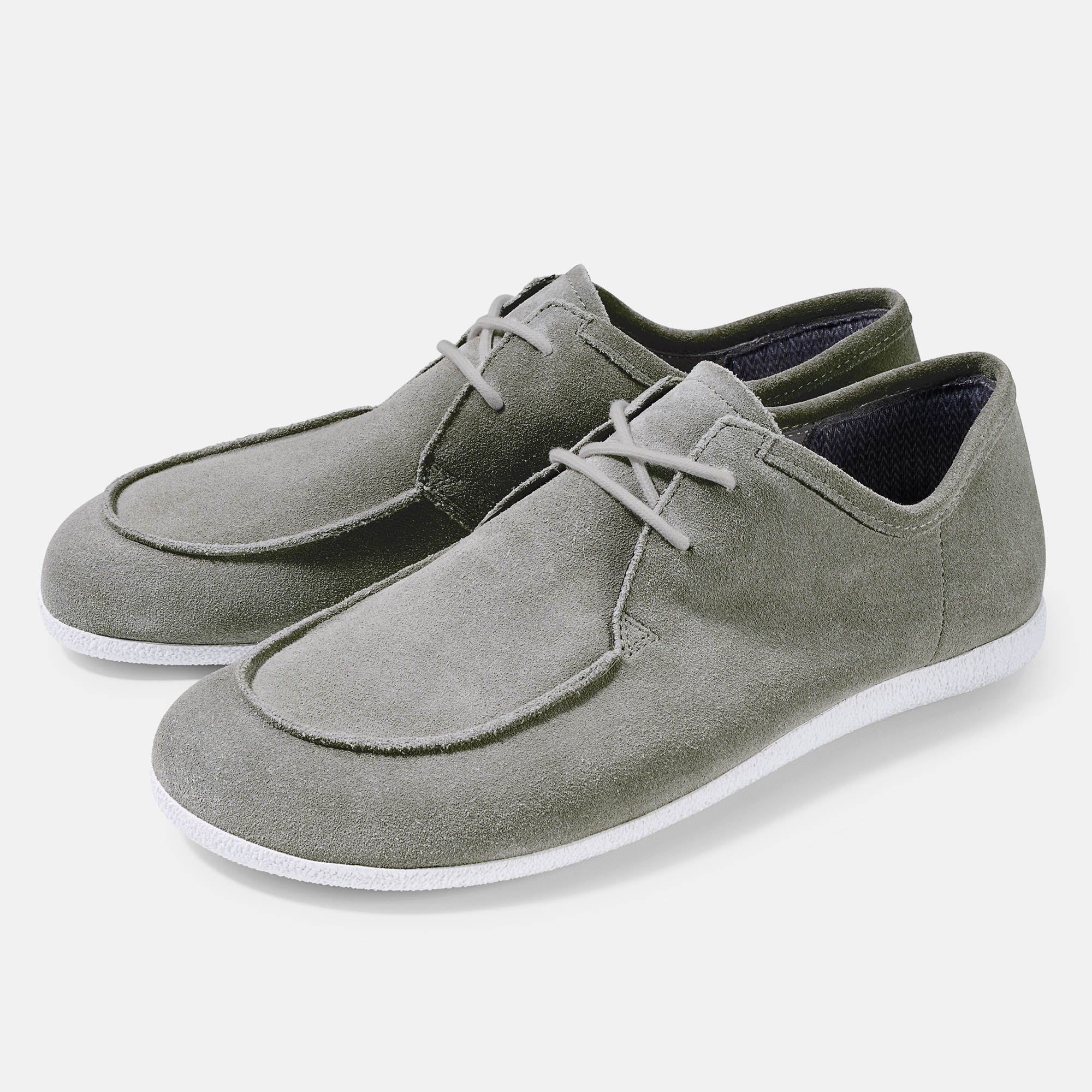 Graue Schnürschuhe mit weißer Sohle. Obermaterial aus Wildleder. Breite Passform. Zwei Schuhe nebeneinander.