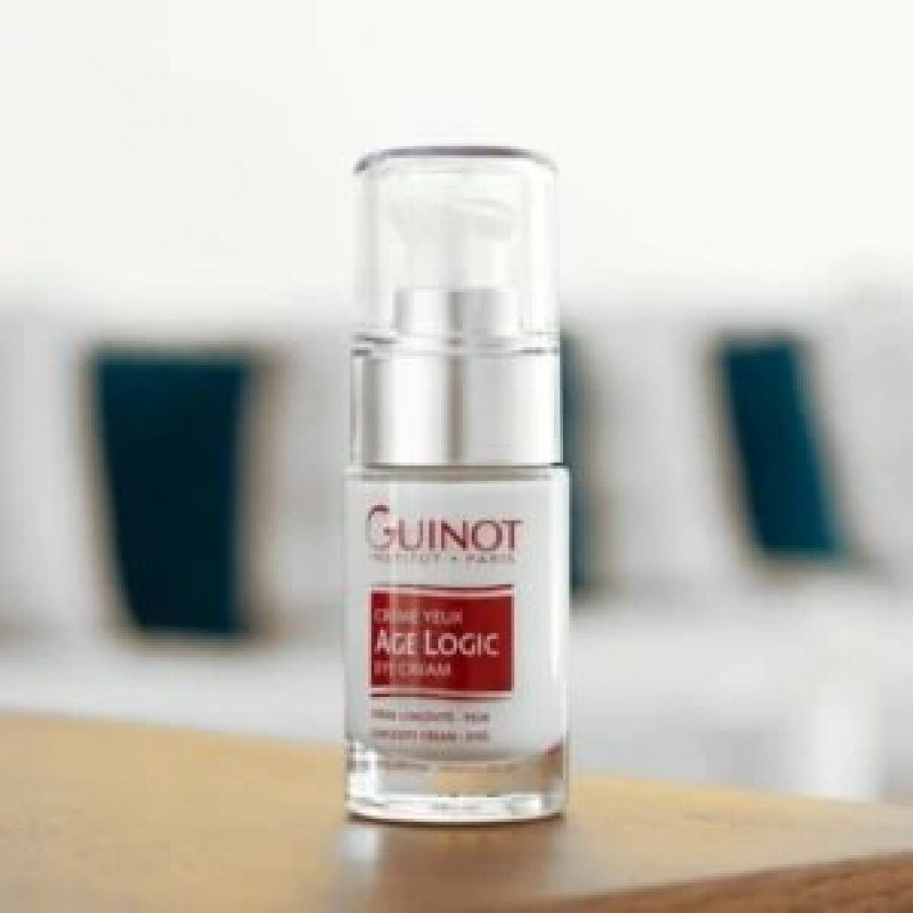 Serumflasche auf Holzoberfläche. Aufschrift: Guinot, Age Logic Eye Cream. Transparente Flasche mit silberner Pumpe und weißem Etikett.