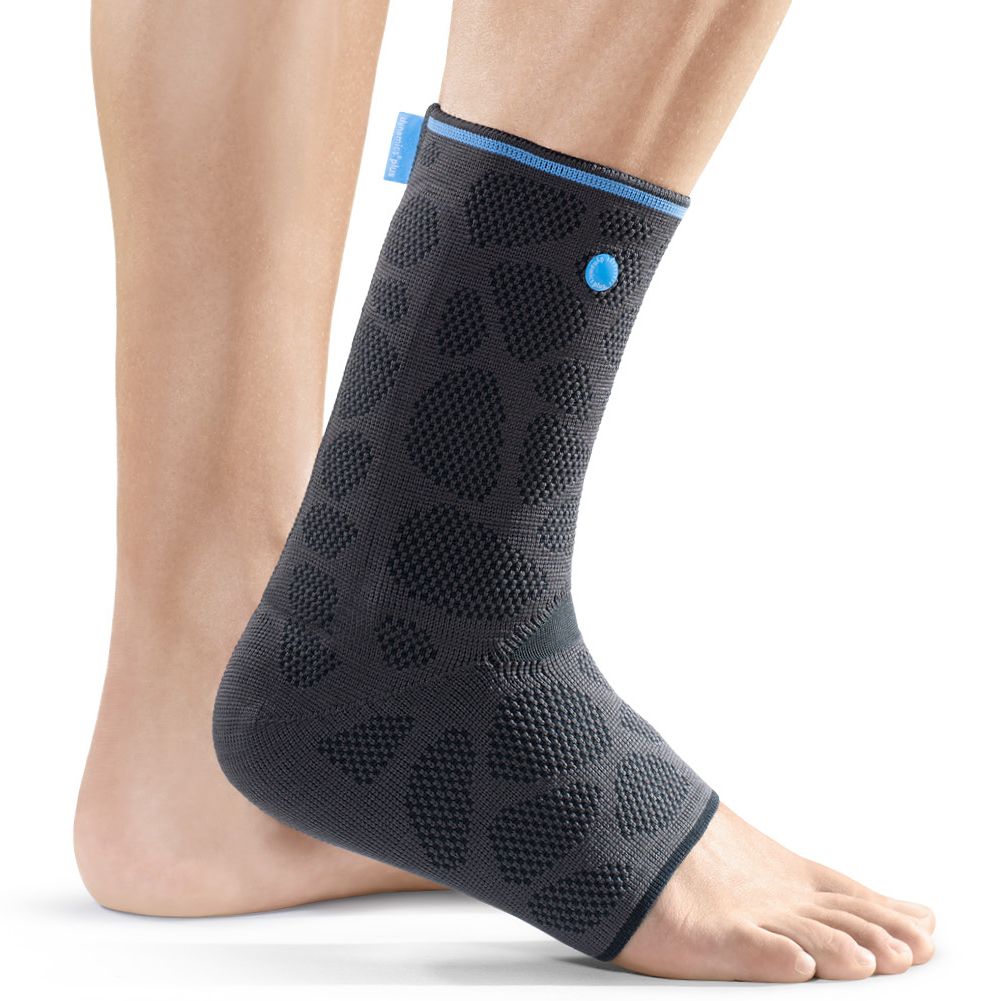 Knöchelbandage, schwarz mit blauen Akzenten, am Bein getragen. Strukturierte Oberfläche mit kreisförmigen Mustern. Blauer Knopf und Akzent.