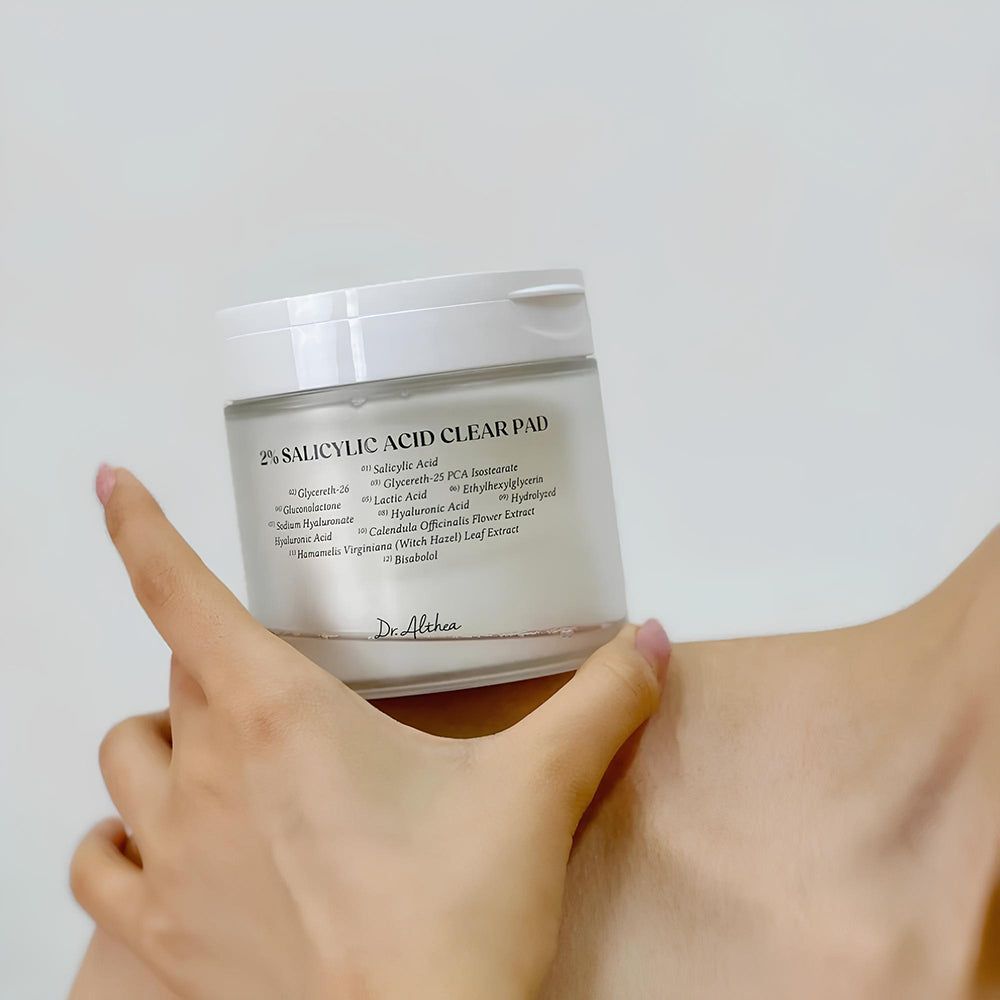 Dr. Althea 2% Salicylsäure Clear Pad in einem Glasbehälter, der von einer Hand gehalten wird.