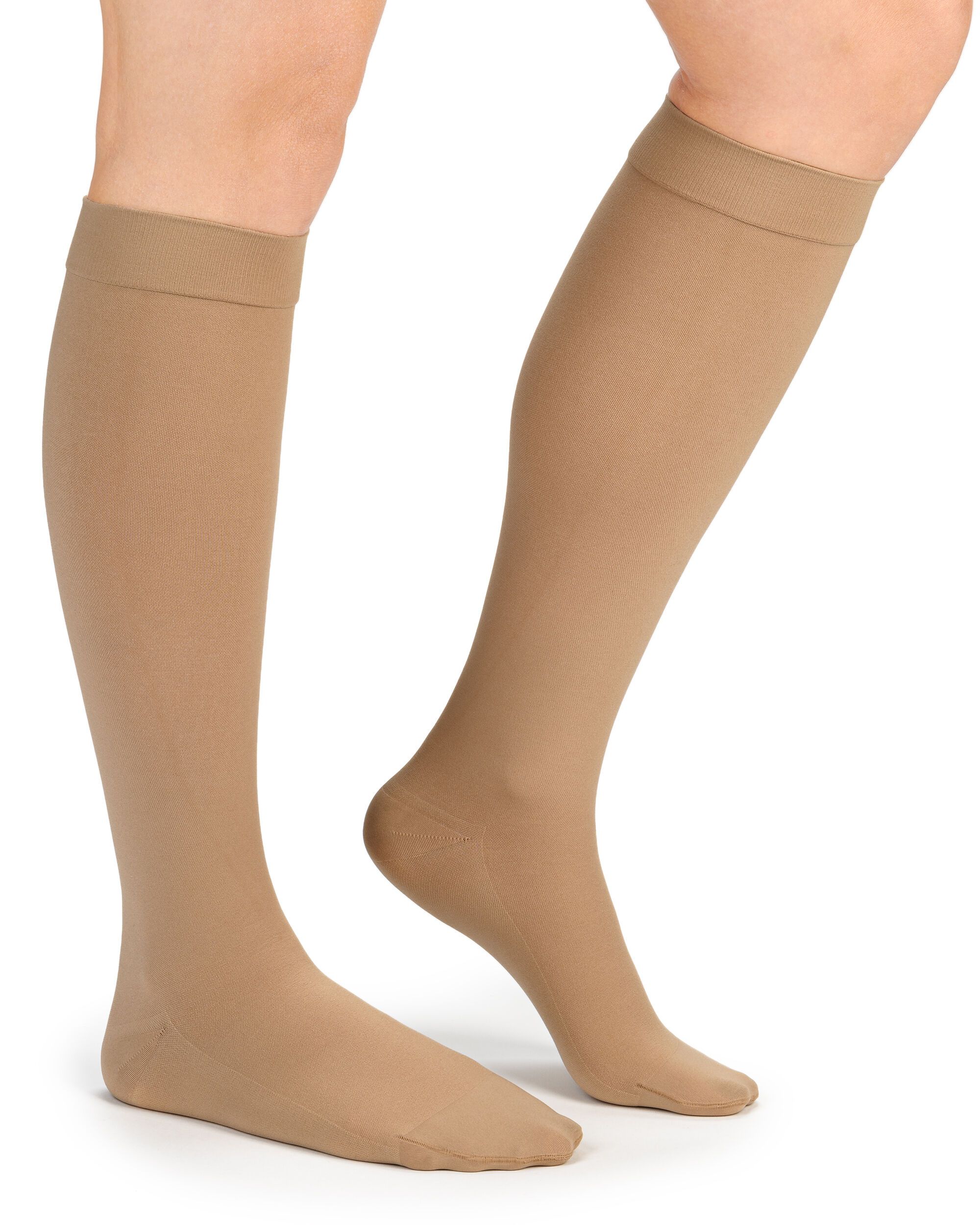 Beige Kompressionsstrümpfe am Bein einer Person. Strümpfe reichen bis unterhalb des Knies.