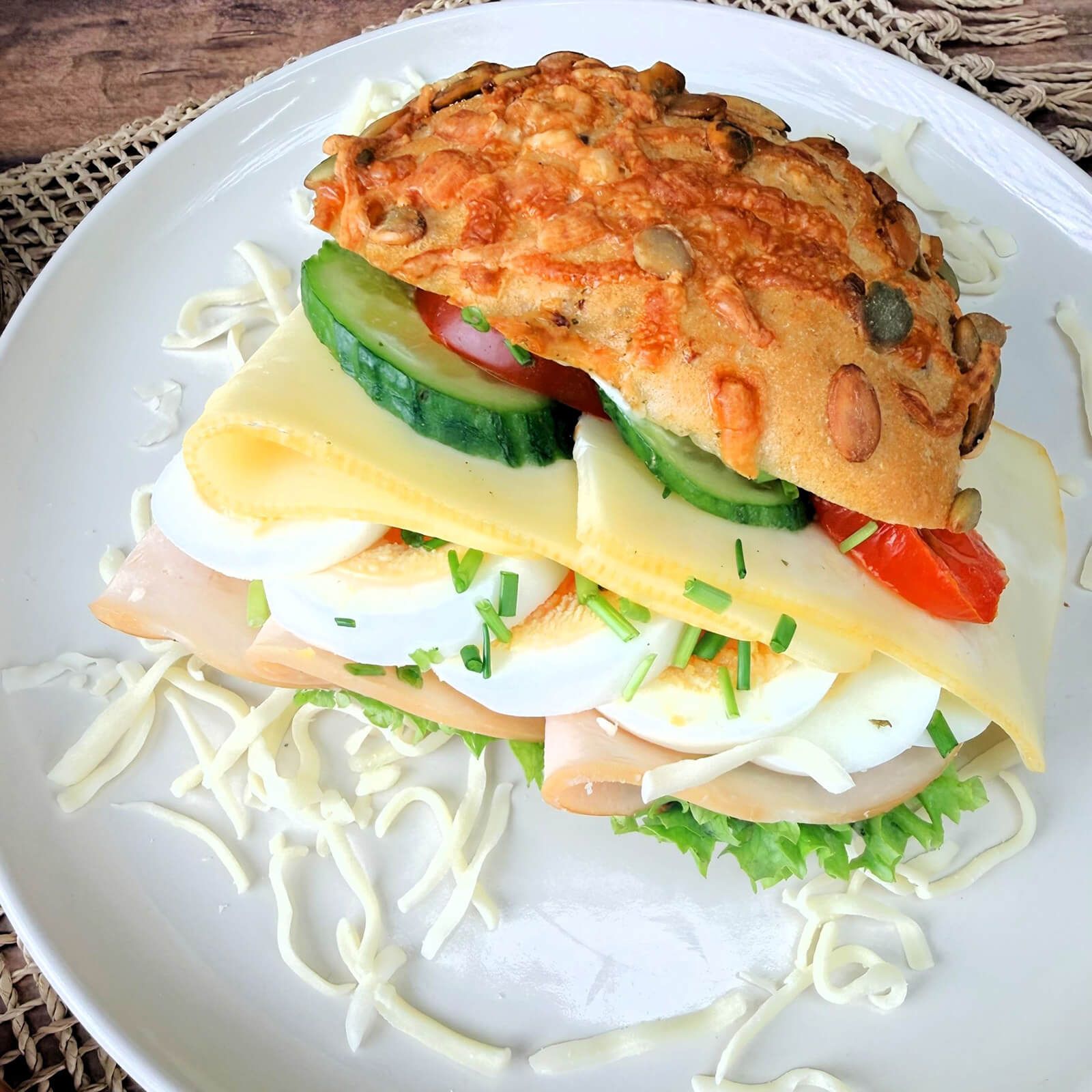 Sandwich mit Kürbis-Käse-Brötchen, Käse, Schinken, Ei, Gurke und Tomate.