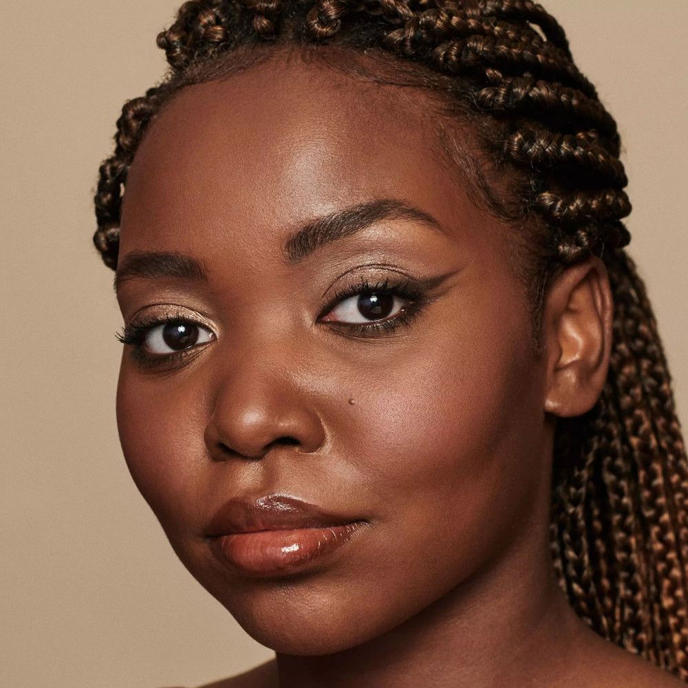 Porträt einer Frau mit braunem Lidstrich. Geformte Augenbrauen. Geflochtene Haare.