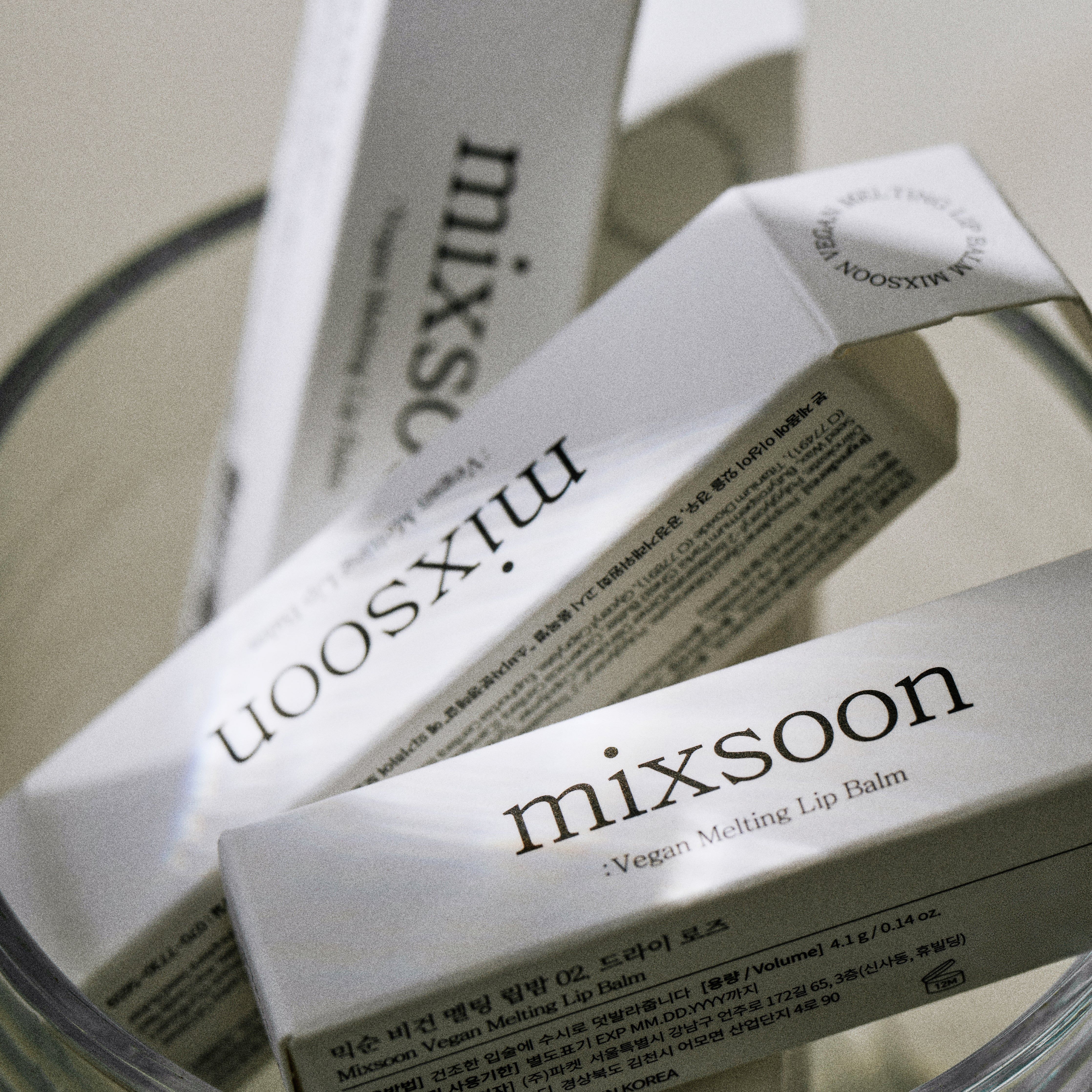 Mehrere Verpackungen von Lippenbalsam in einem Glas. Auf den Verpackungen steht "mixsoon Vegan Melting Lip Balm".