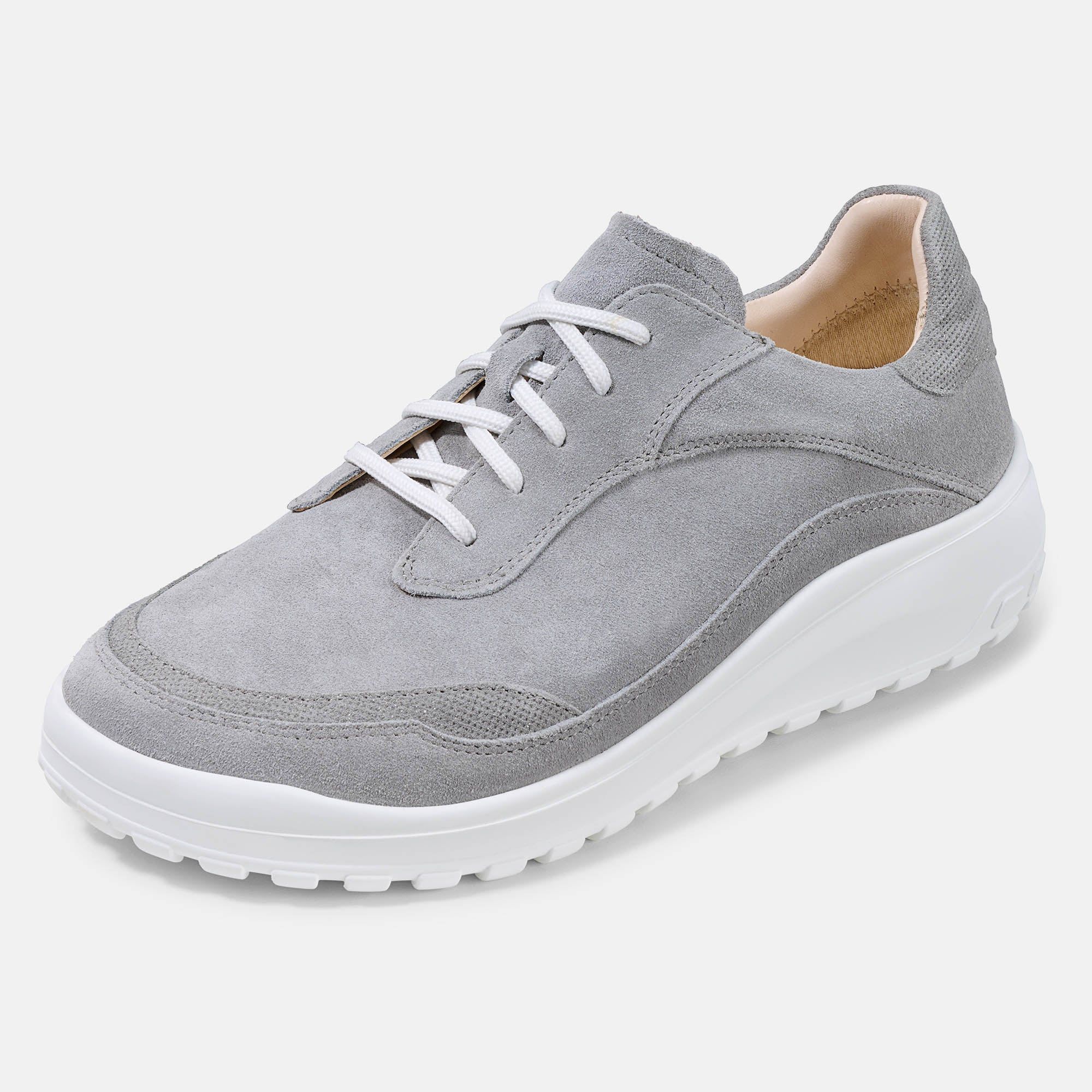 Grauer Schnürschuh mit weißer Sohle. Breiter Schnitt. Hellgraues Wildleder-Obermaterial. Weiße Schnürsenkel. Schuh von vorne.