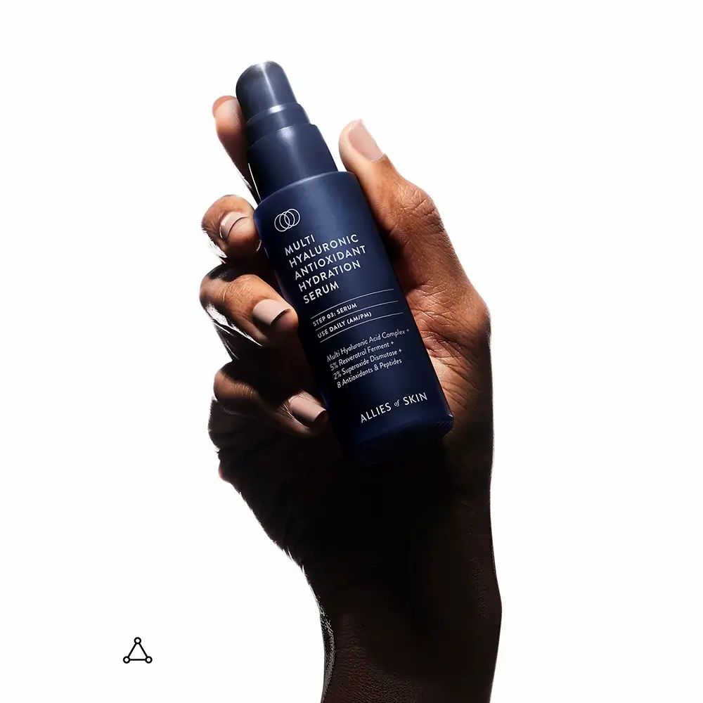 Hand hält eine Flasche mit Pumpe. Aufschrift: Multi Hyaluronic Antioxidant Hydration Serum. Marke: ALLIES OF SKIN.