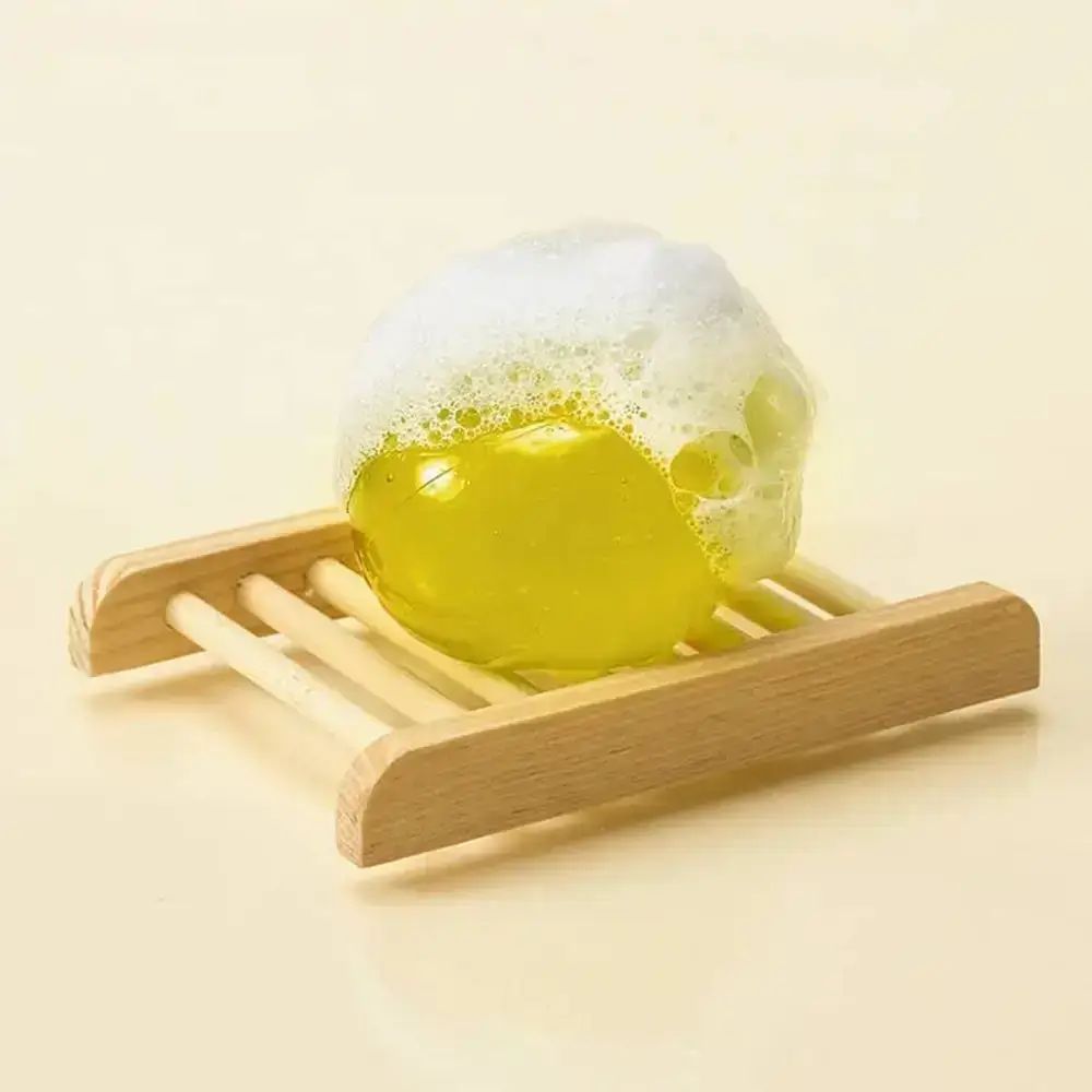 Gelbe Kugel auf Holzseifenablage mit Schaum bedeckt.
