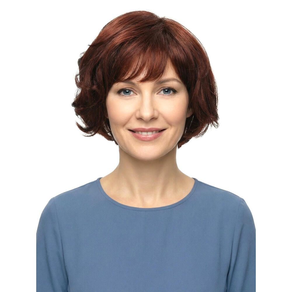 Frau mit roter Perücke. Kurzer, gewellter Haarschnitt mit Pony. Blauer Pullover. Frontalansicht.