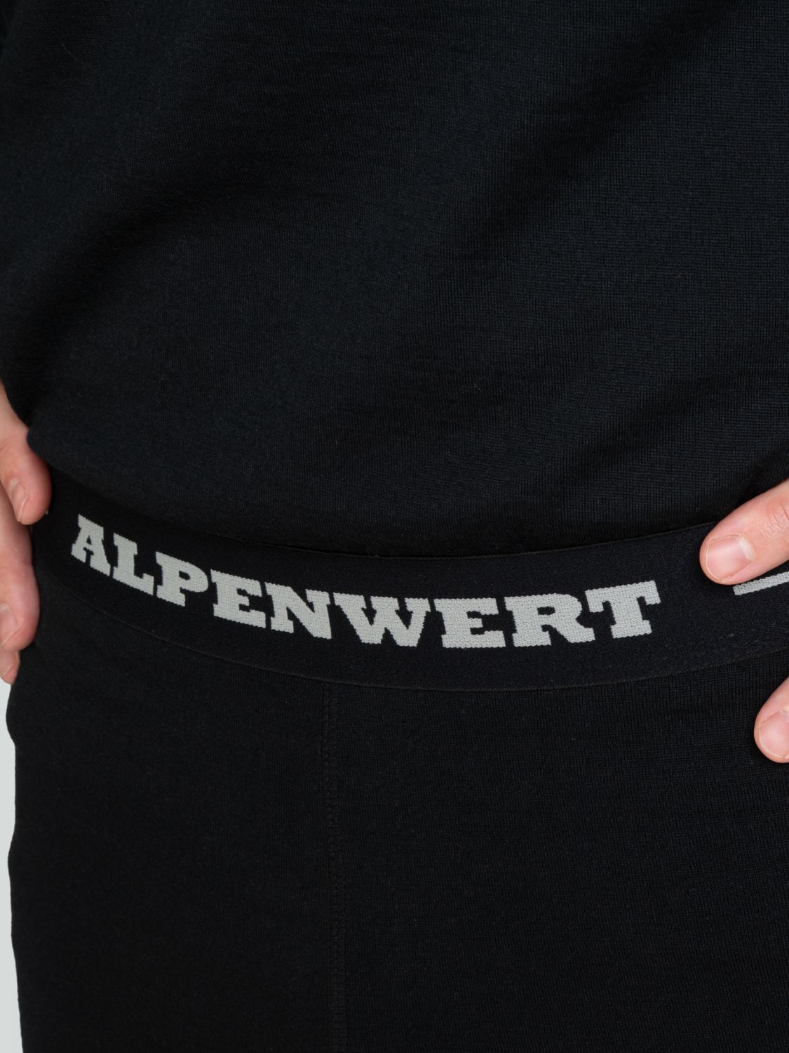 Nahaufnahme des Bundes einer schwarzen langen Unterhose aus Merinowolle mit dem Schriftzug ALPENWERT.