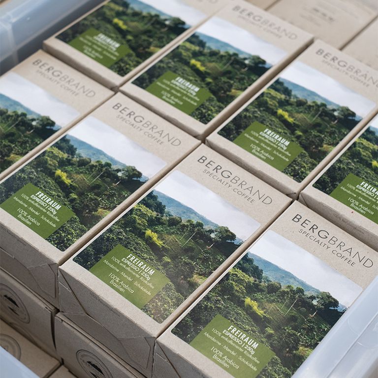 Mehrere Kaffeepackungen mit Landschaftsbild. Text: BERGBRAND, Freiraum Espresso, 100% Arabica, Brasilien.
