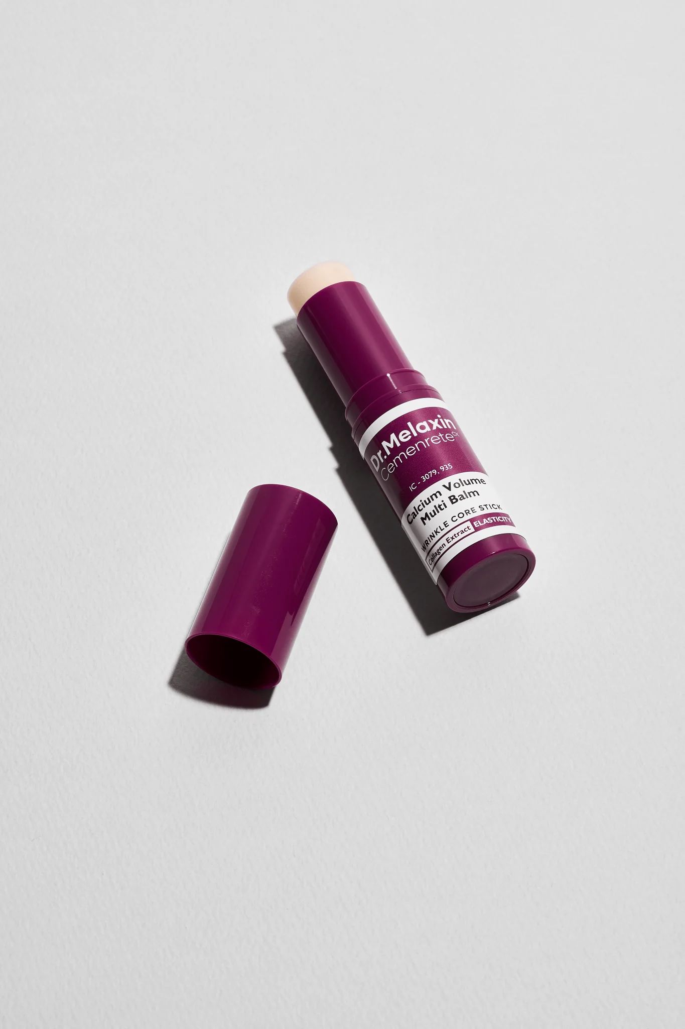 Dunkellila Balm mit geöffneter Kappe. Aufschrift: Dr.Melaxin Cemenrete Calcium Volume Multi Balm. Weißer Text.