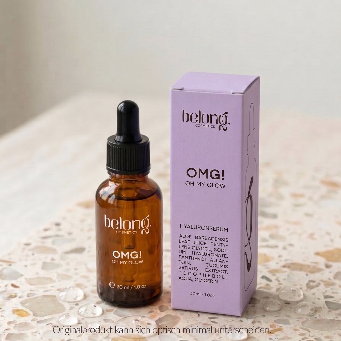 Belong. Cosmetics OMG! Hyaluronserum neben seiner lila Umverpackung auf einer strukturierten Oberfläche.