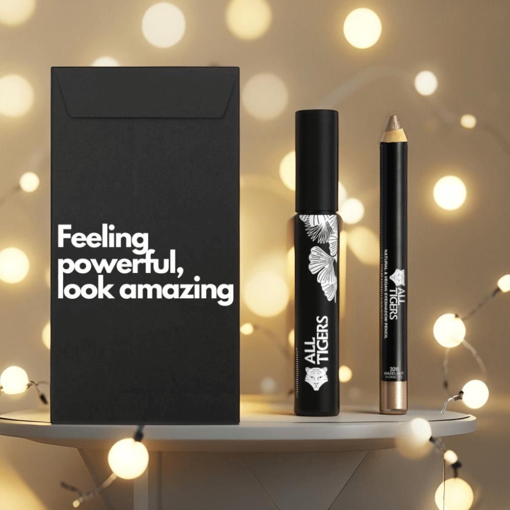 Schwarze Verpackung mit Text. Mascara und Stift daneben. Mascara mit weißem Muster und Logo. Stift mit goldener Spitze. Lichter.