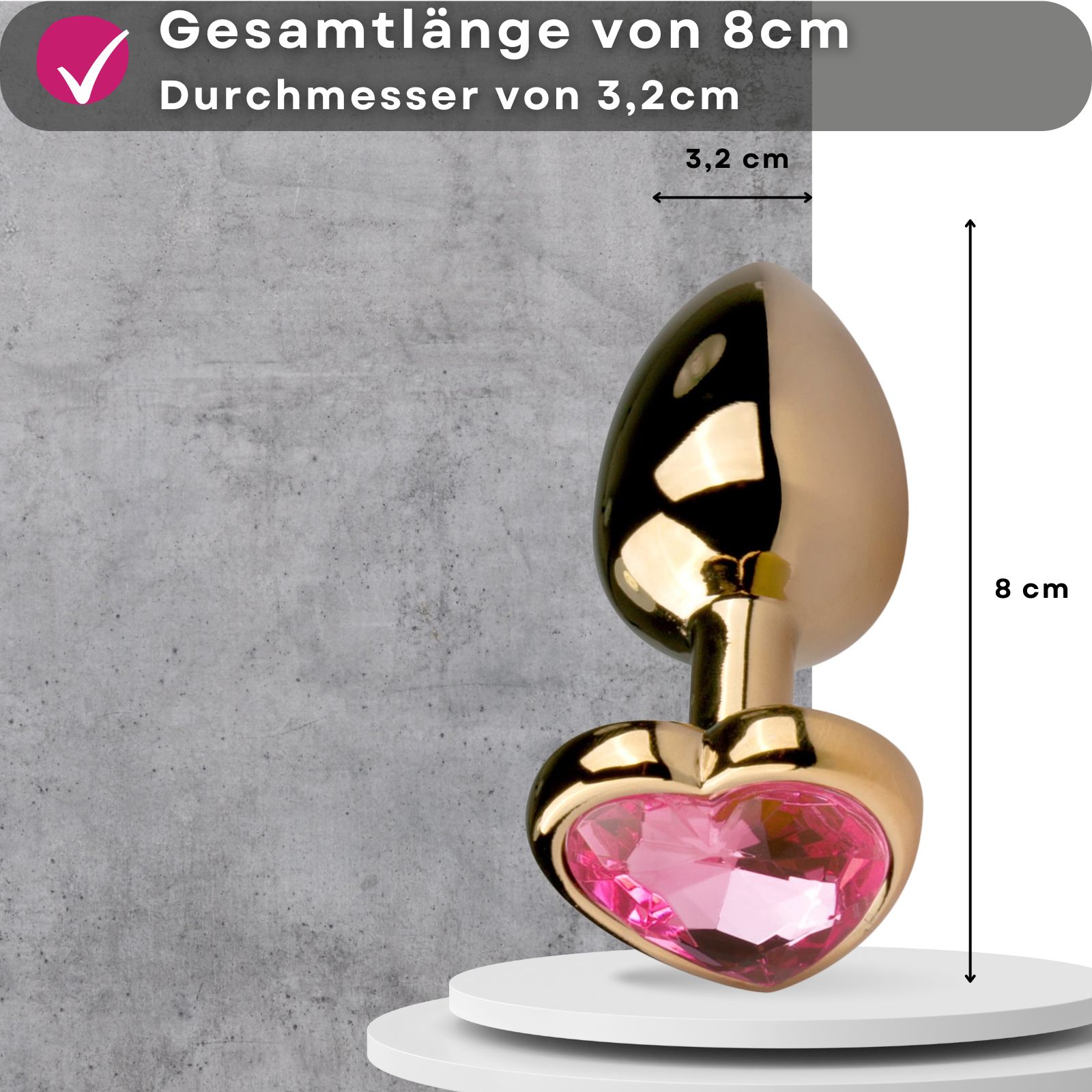 Goldfarbener Analplug mit herzförmigem Zierstein. Gesamtlänge 8cm, Durchmesser 3,2cm. Auf Podest.