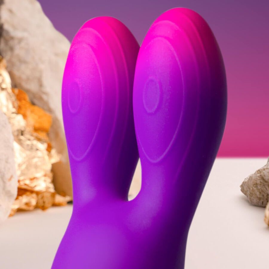 Nahaufnahme des lila Vibrators mit Hasenohren-Design. Farbverlauf von Lila zu Pink. Auf weißem Untergrund.