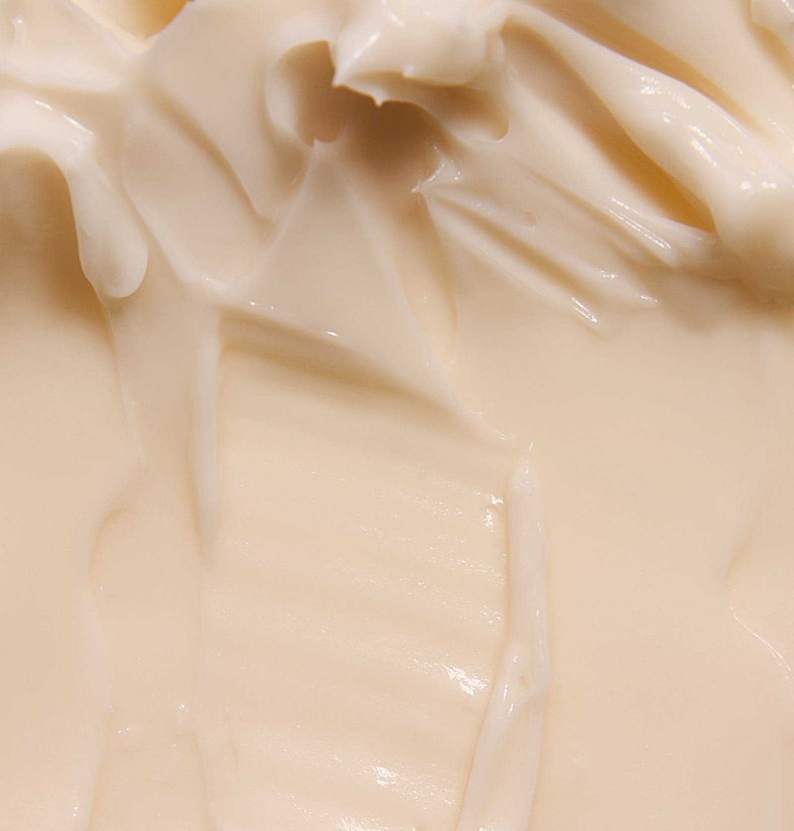 Nahaufnahme einer cremigen, hellbeigen Substanz. Die Textur ist uneben und wellig.