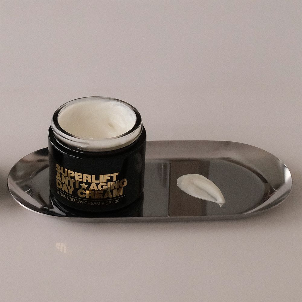 Offener schwarzer Tiegel mit Creme auf silberner Tablett. Text: Superlift Anti-Aging Day Cream.