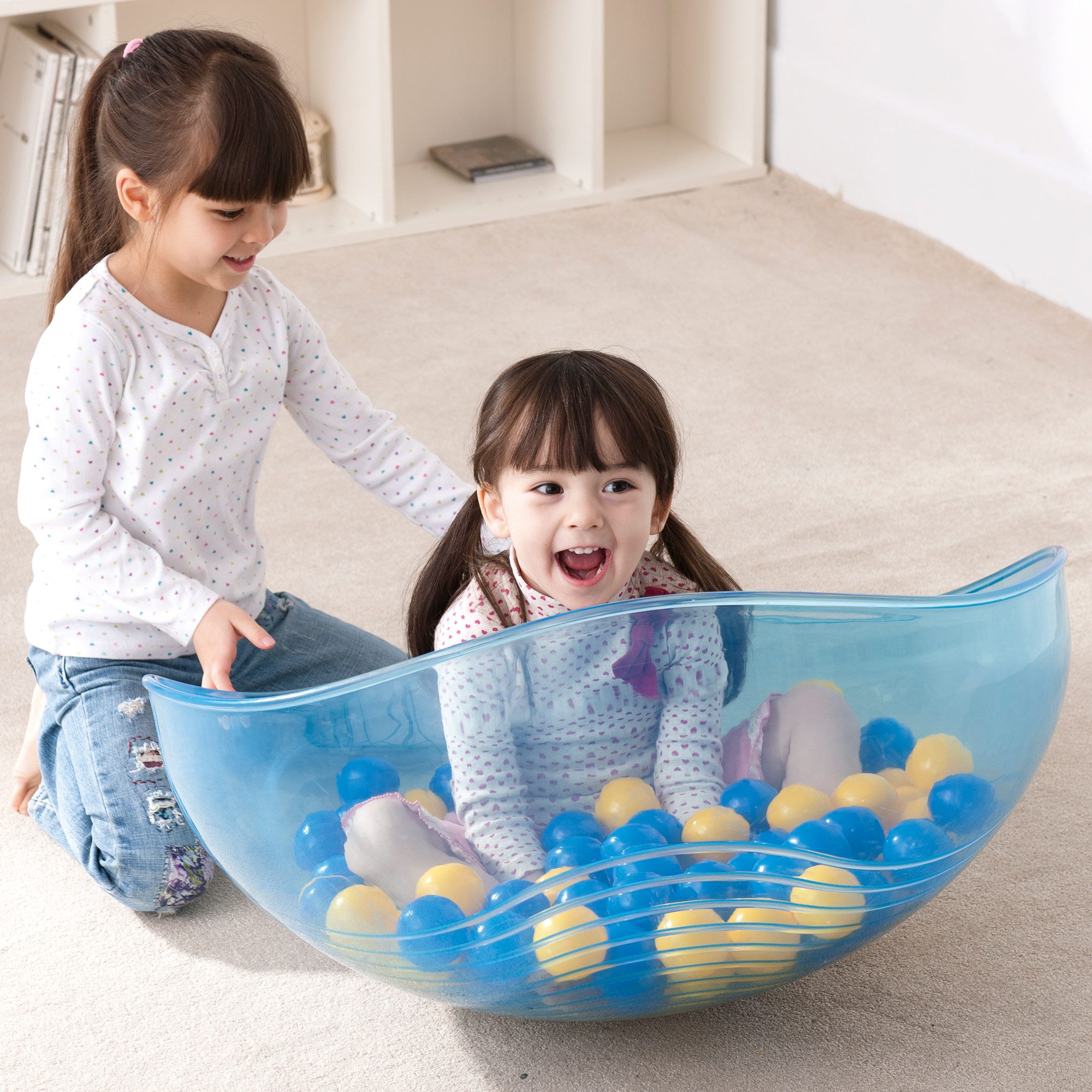 Blau transparente Schale mit Bällen. Zwei Kinder spielen damit.